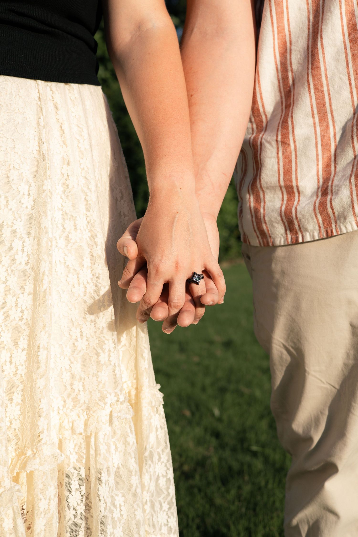 Close-up of couple holding hands against cream colored background outdoors.