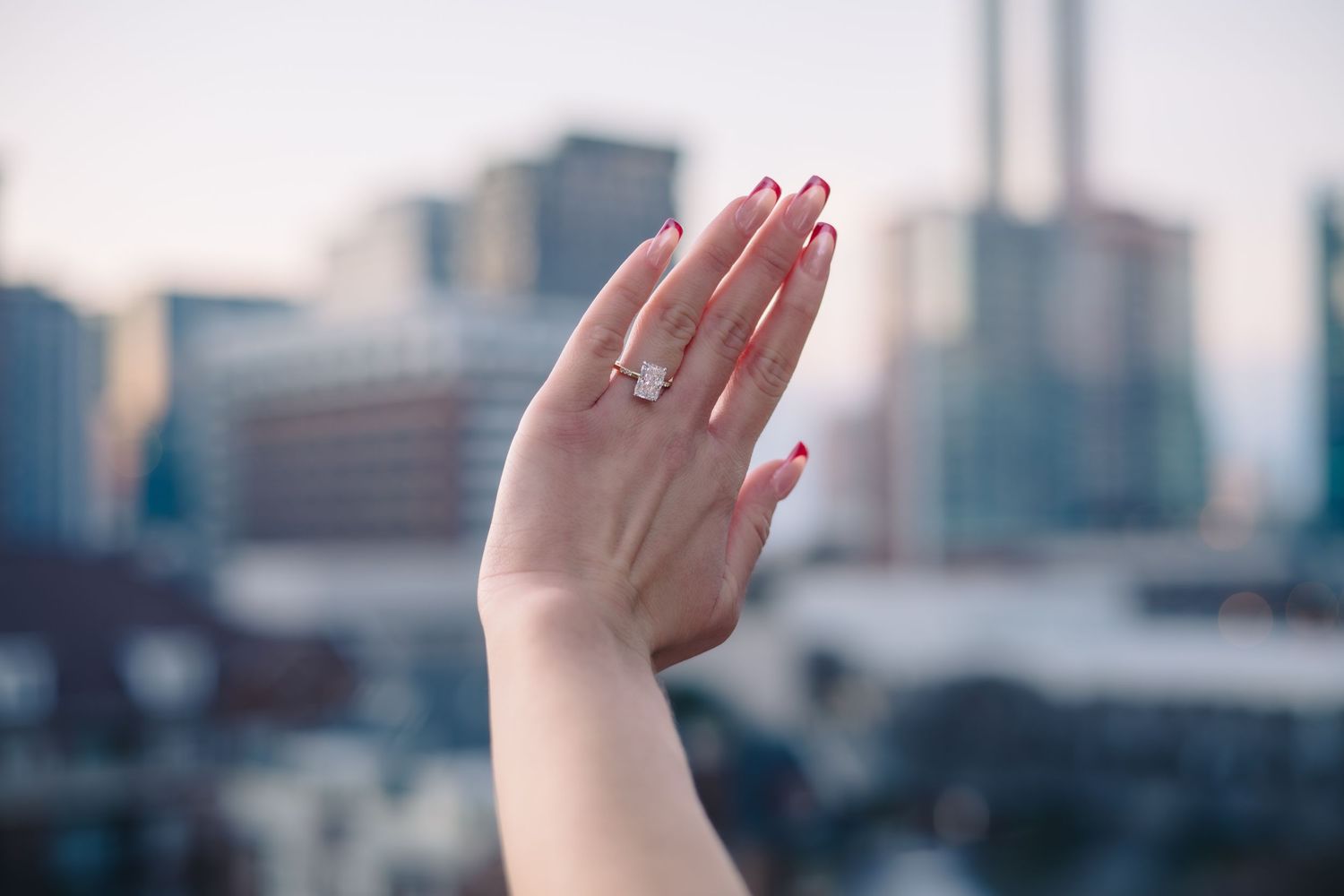 Raised hands silhouetted against a blurred city skyline background.