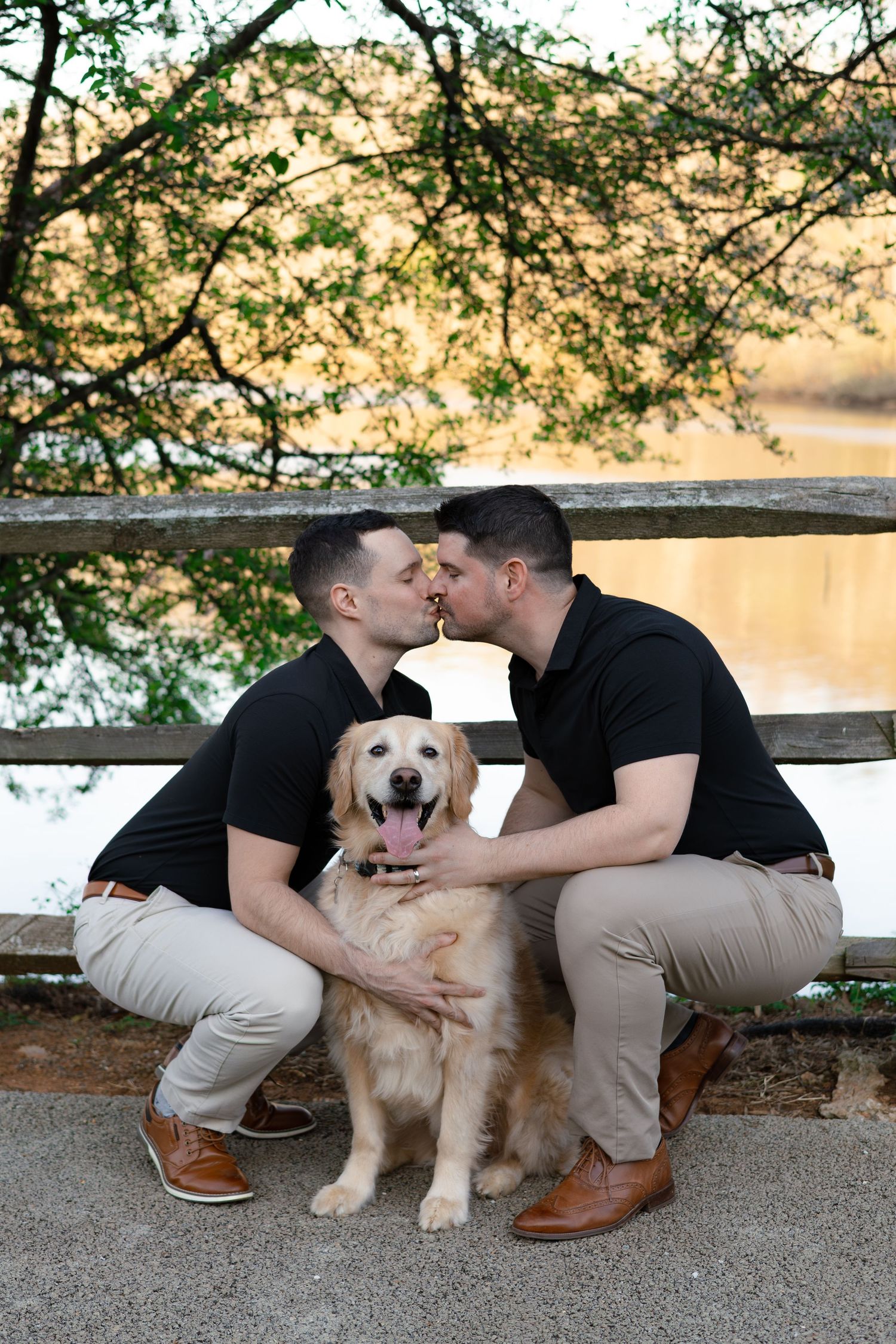 A couple shares a tender moment on a bench at sunset with their happy Golden Retriever sitting between them.