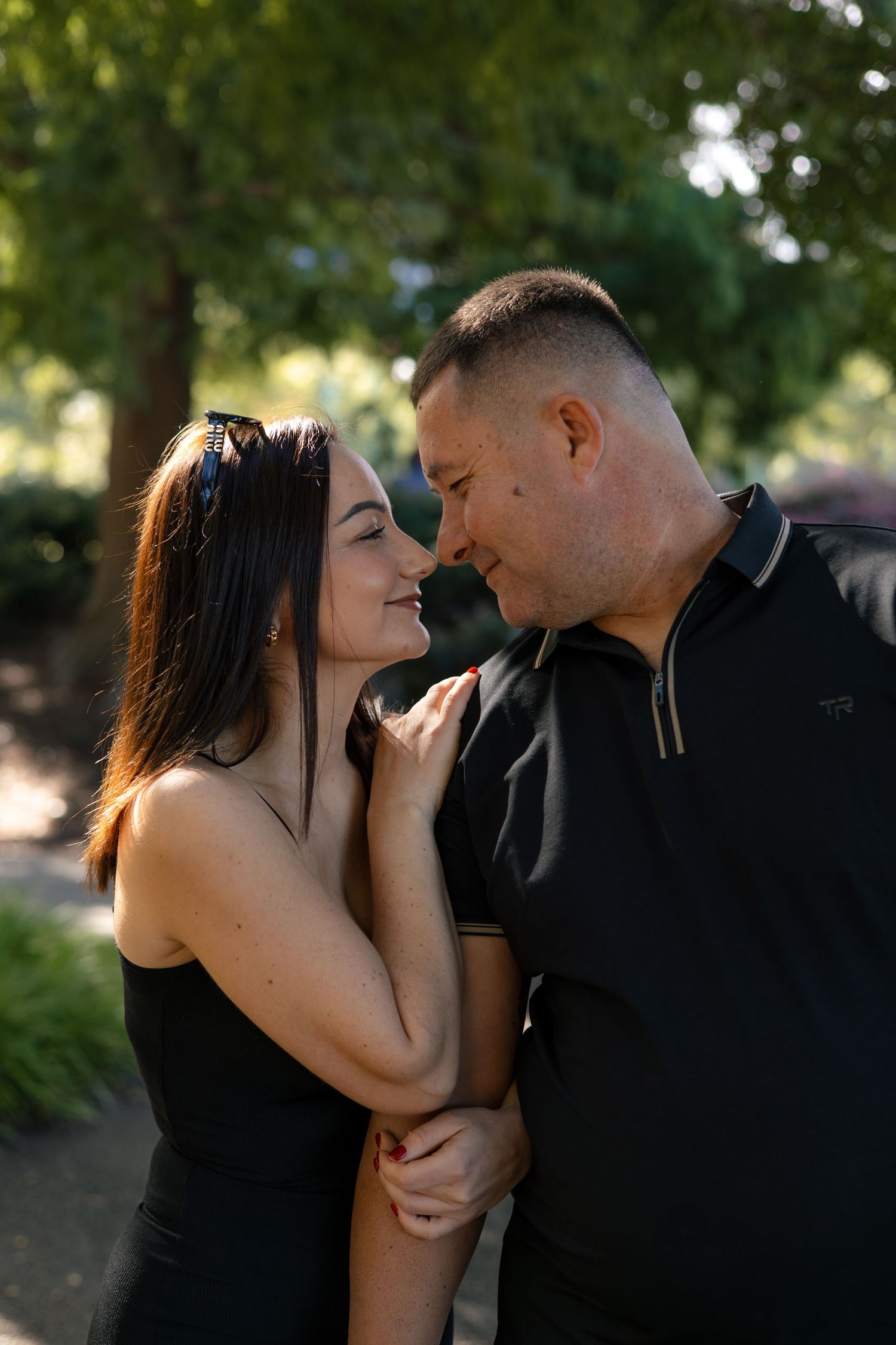 Intimate couple portraits captured in golden sunlight under trees.