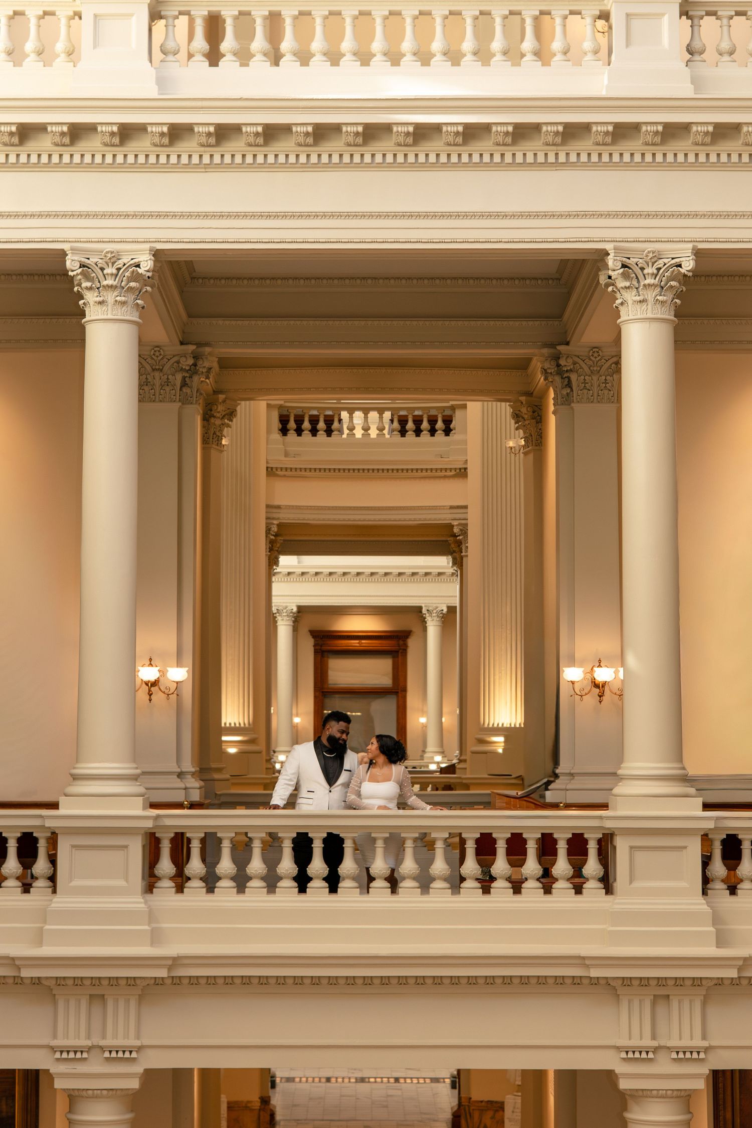 Grand interior architecture with classical columns and balustrades in warm lighting.