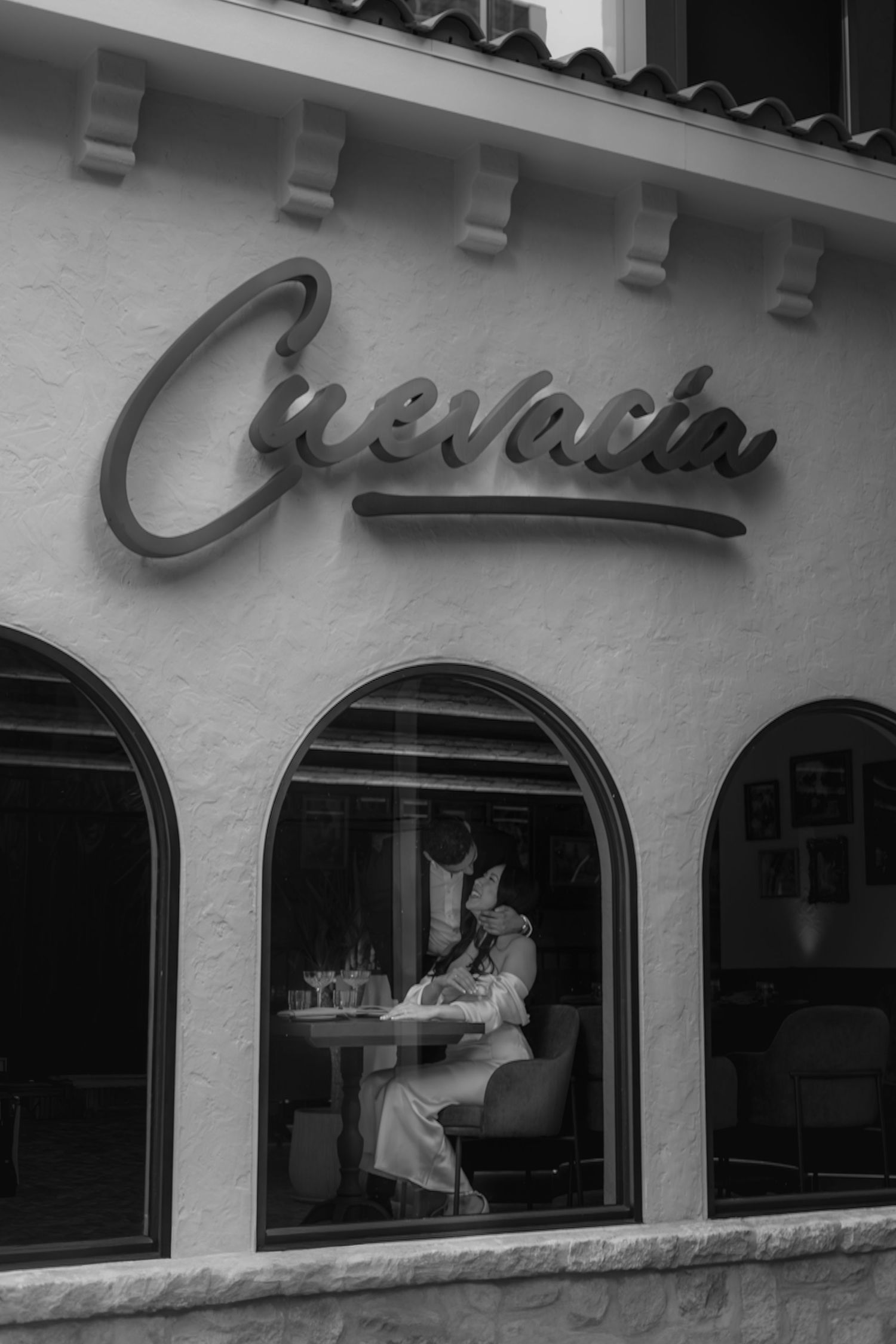Black and white exterior view of restaurant with arched windows and signage.