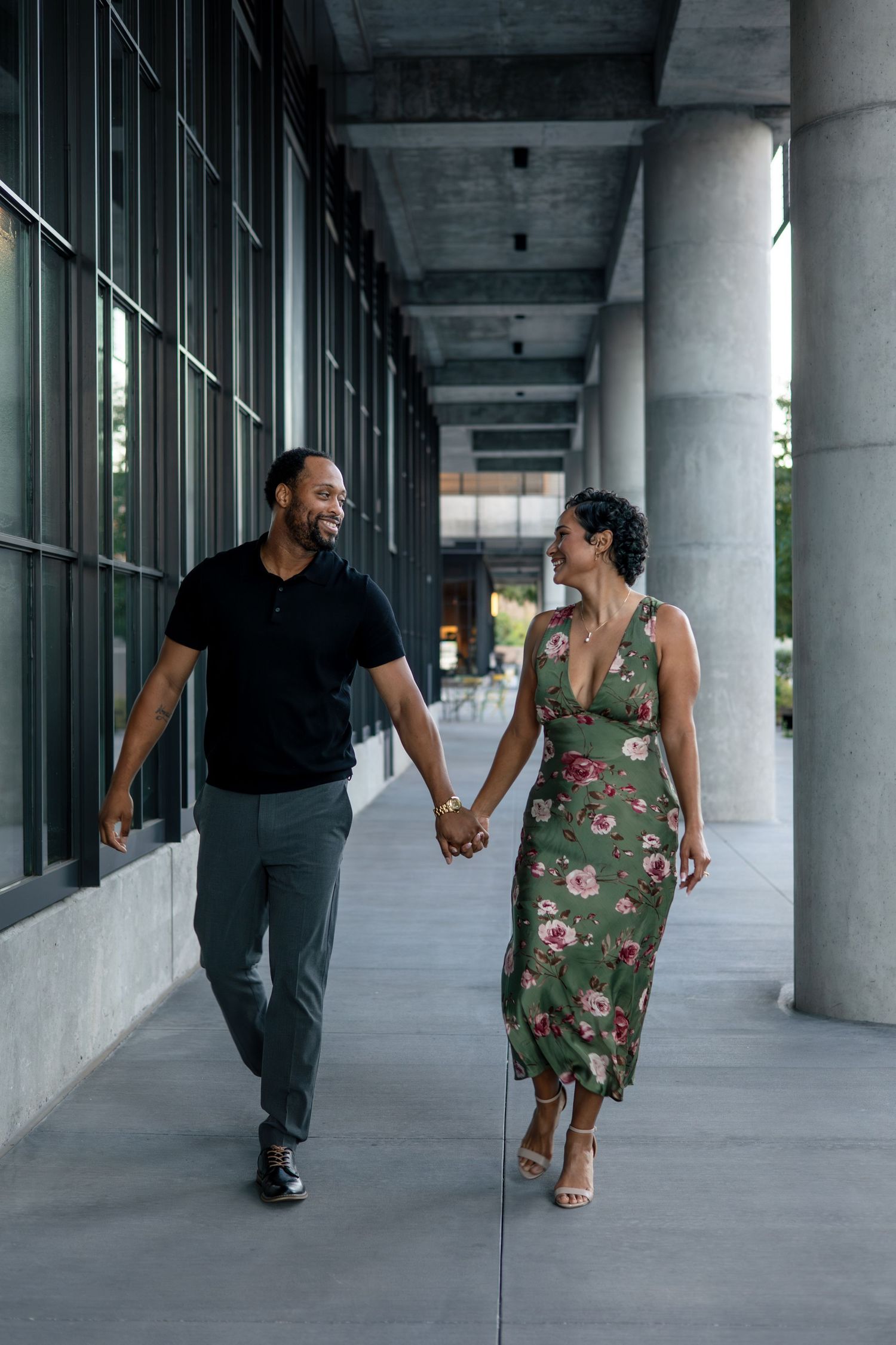 Couple walking and laughing together through modern architectural corridor.