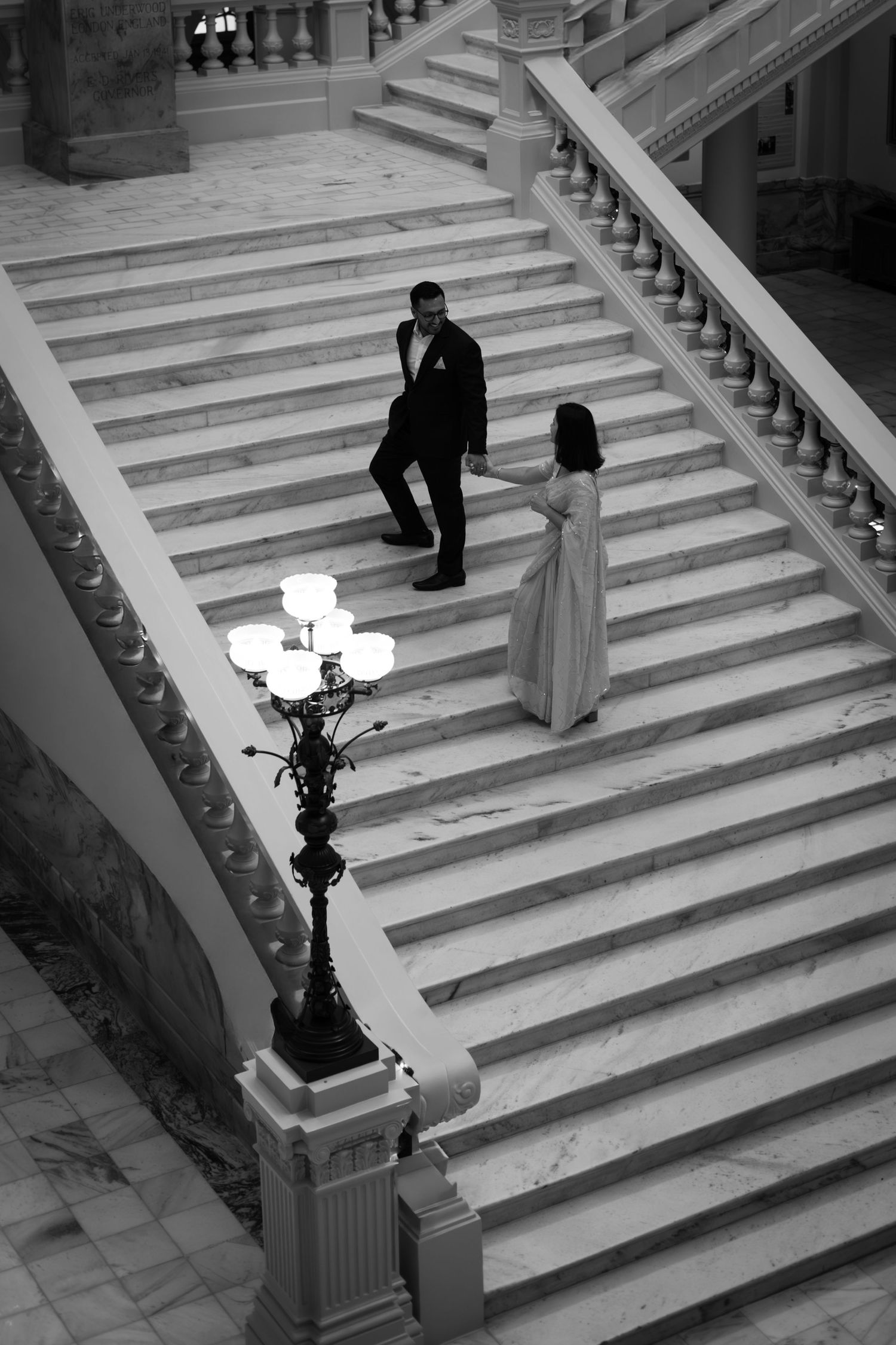 A dramatic black and white proposal scene on grand marble stairs.