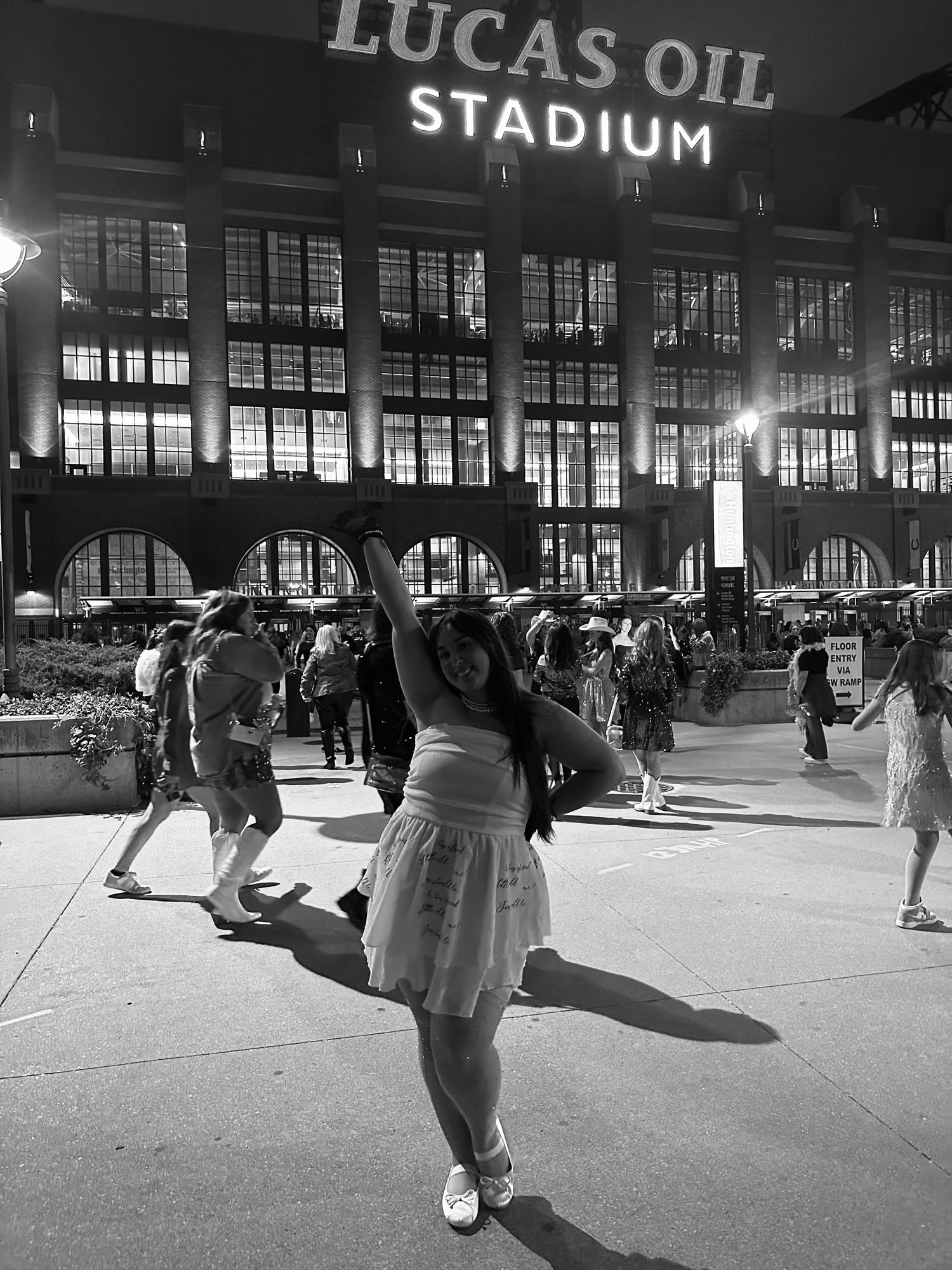 People pose playfully outside Lucas Oil Stadium in black and white photography.