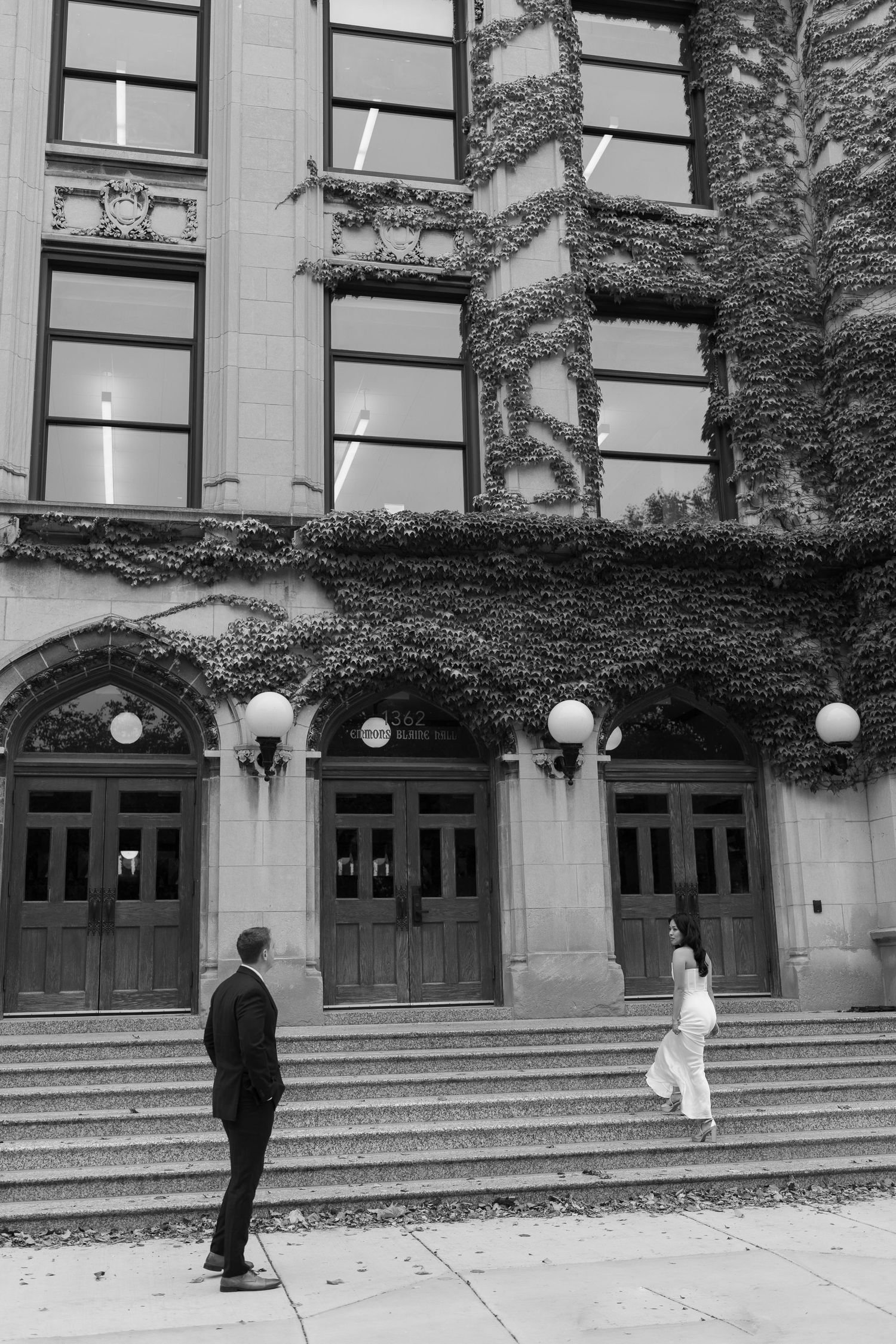 A romantic scene at an ivy-covered building entrance with grand wooden doors and stone steps.