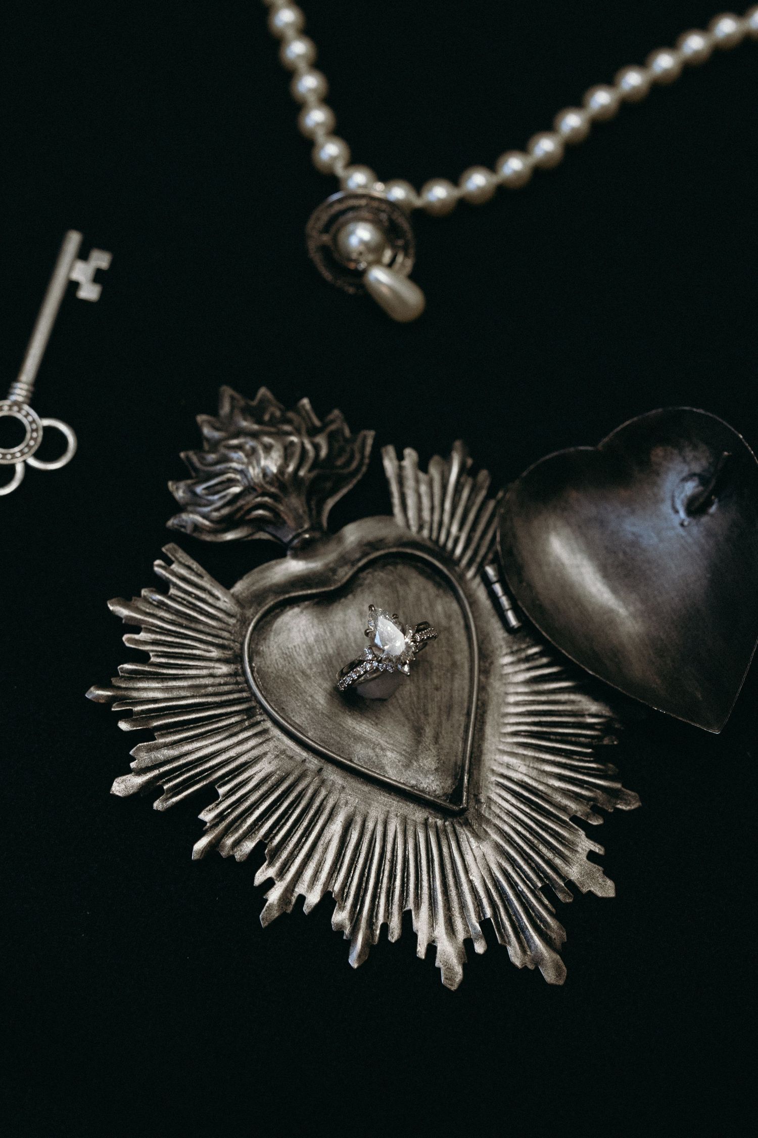 A vintage-style metal heart pendant with sunburst rays photographed in a dark setting.