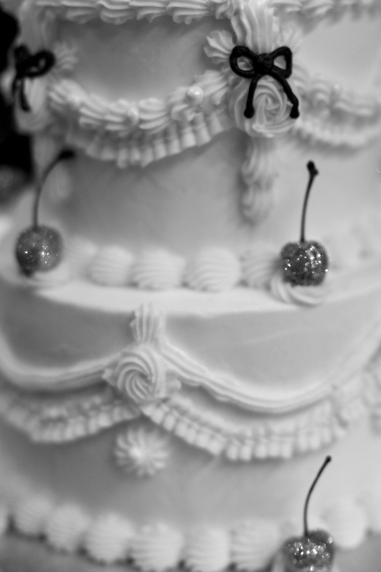 Close-up details of white wedding cake with delicate piped frosting decorations.