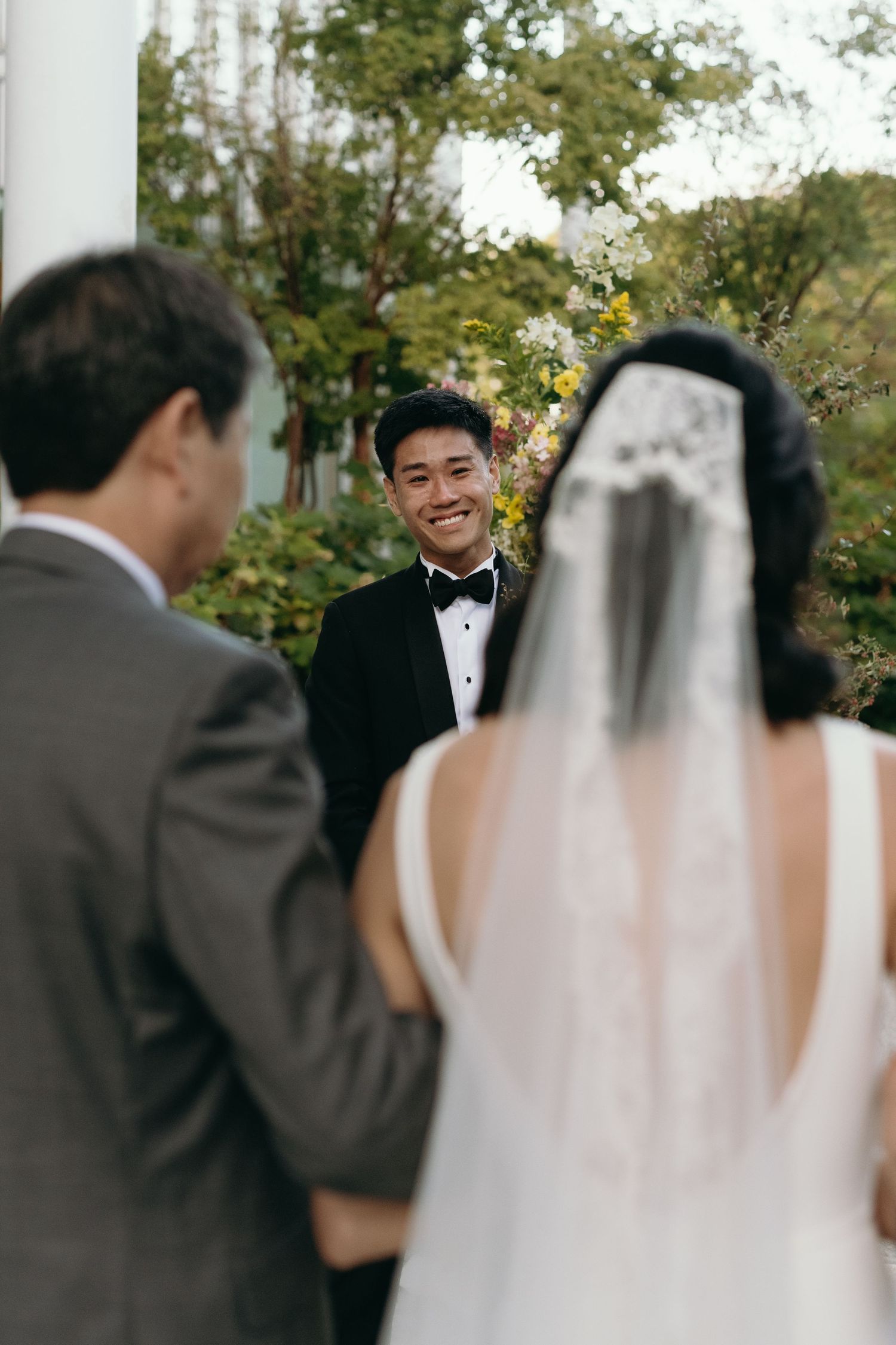 Outdoor wedding ceremony with white columns and natural garden backdrop.