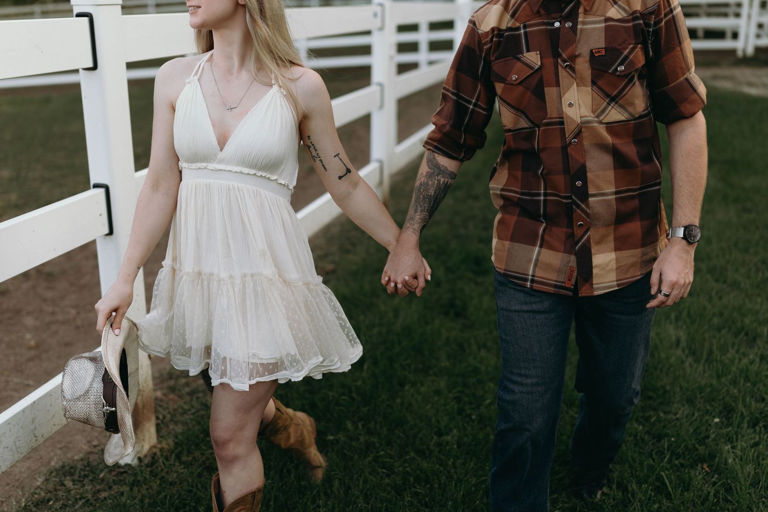 A romantic couple enjoying a carefree moment outdoors near a white picket fence.
