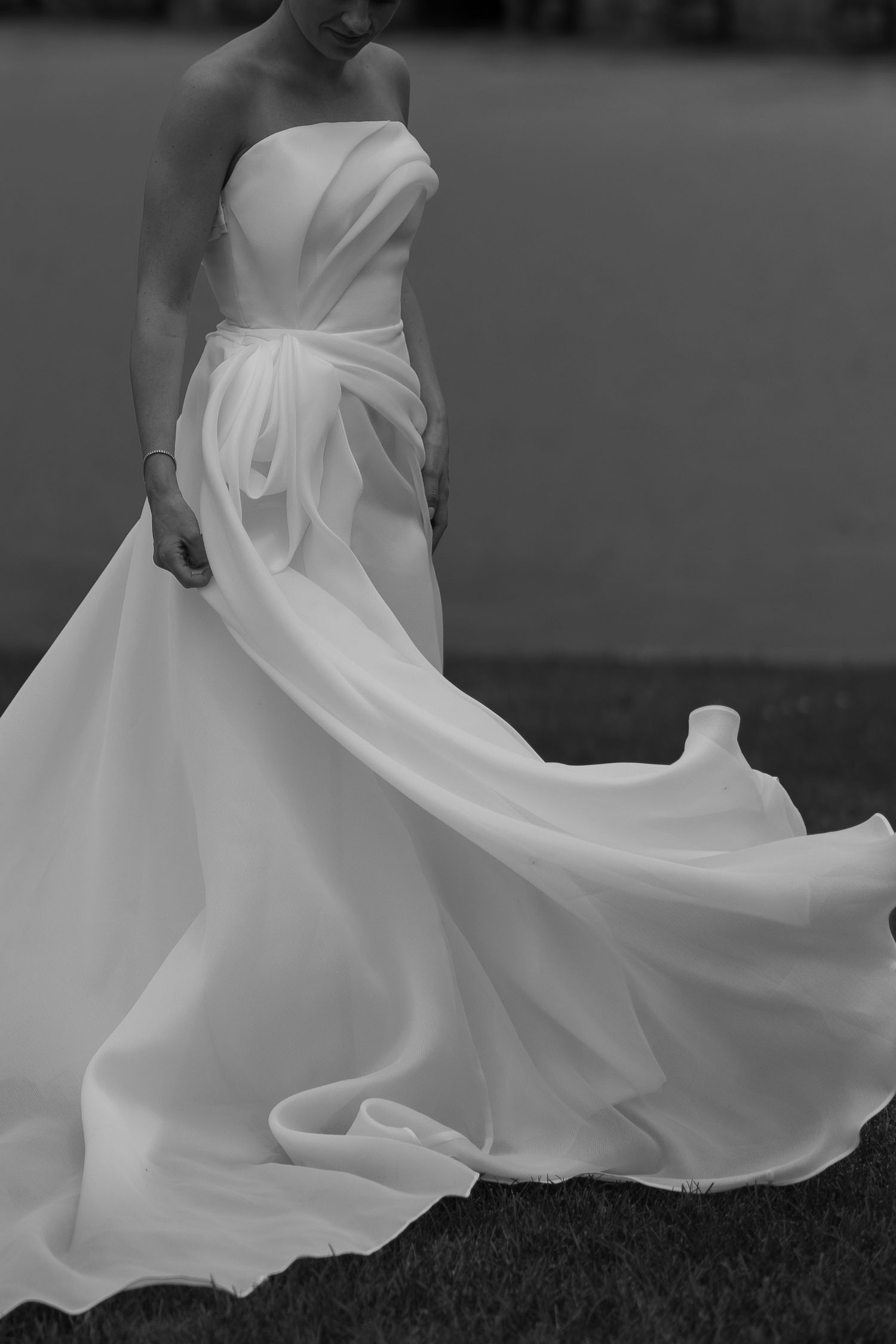 White wedding dress fabric flowing and twirling gracefully in the wind against a dark background creates an elegant motion shot.