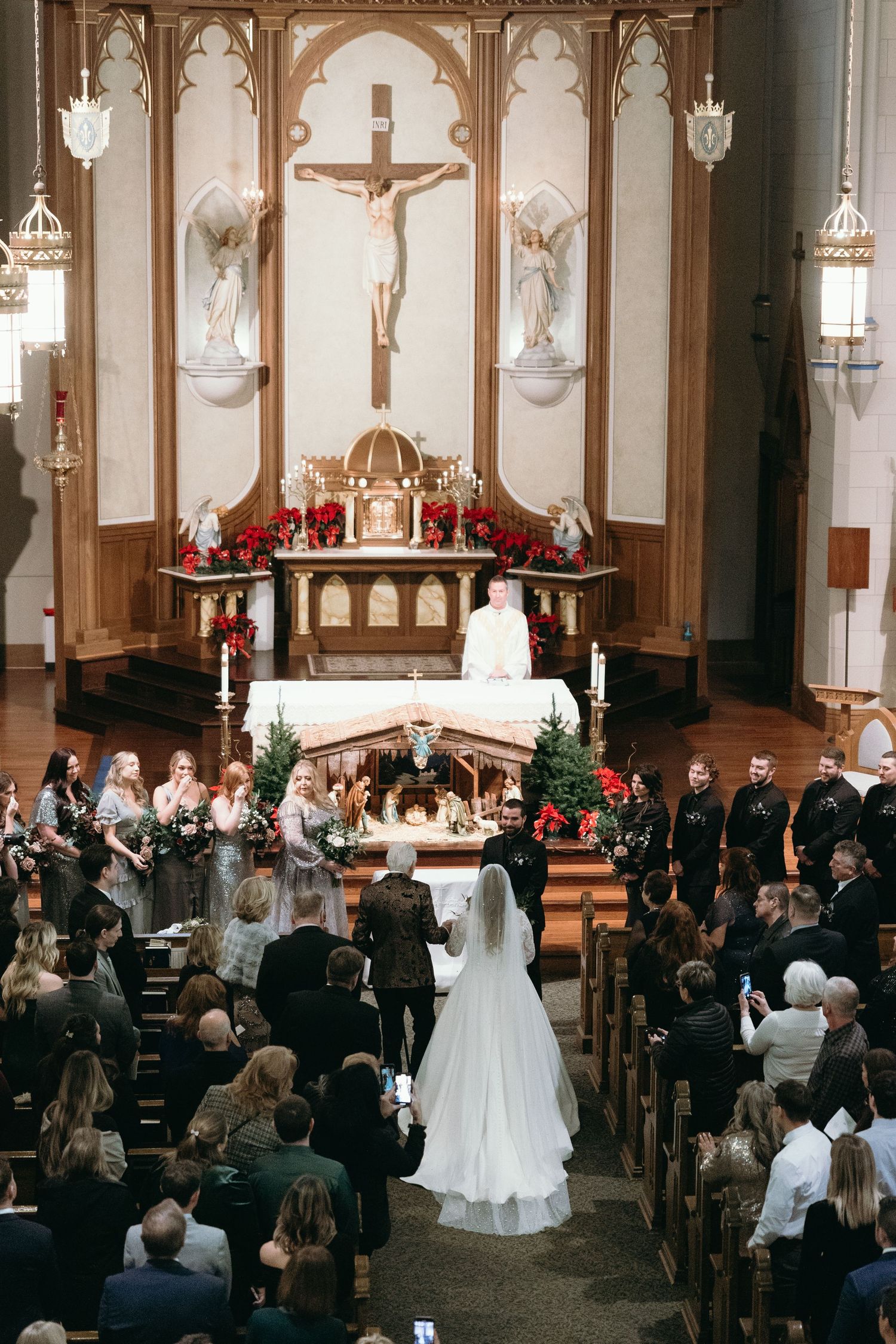 Traditional Catholic church wedding ceremony with crucifix altar and gathered congregation in wooden pews.