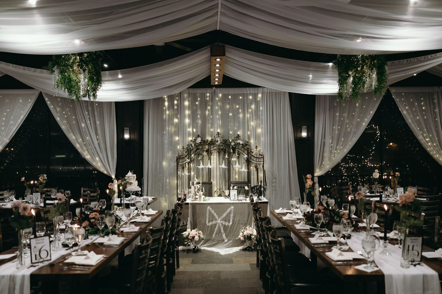 Elegant wedding reception hall with draped fabric ceiling, crystal chandeliers and intimate table settings.