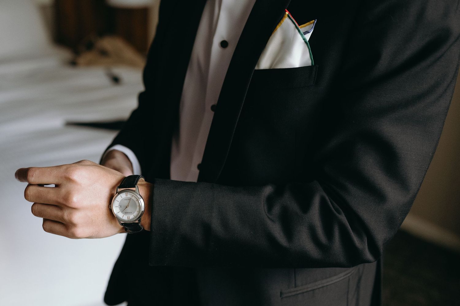 Detail shot of groom checking watch while wearing classic black tuxedo.