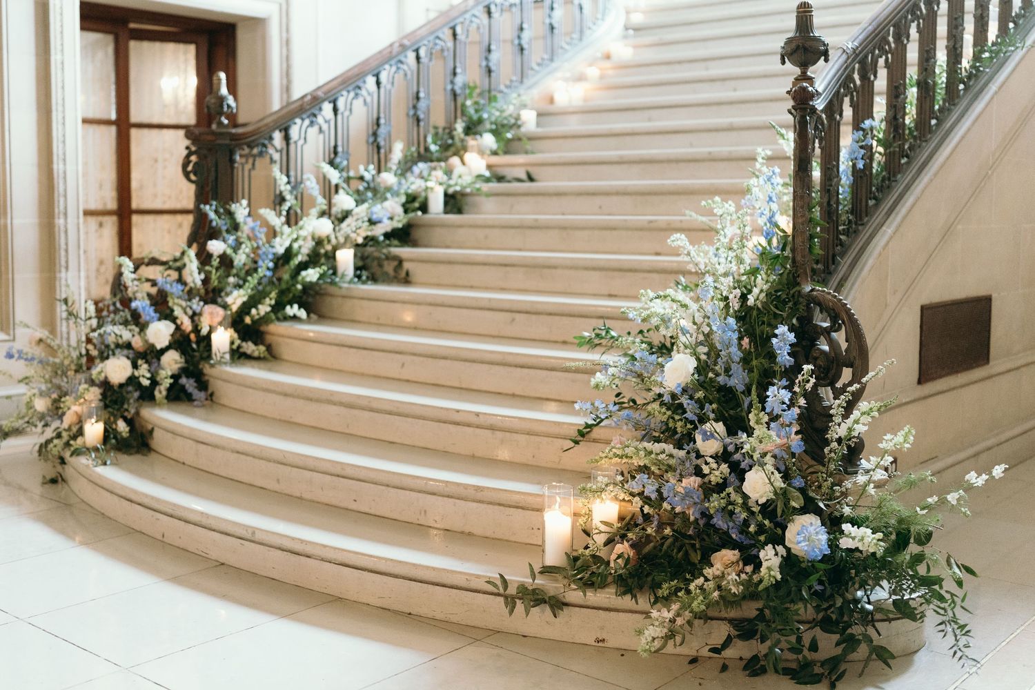 Elegant staircase decorated with white floral arrangements and greenery for a wedding ceremony.