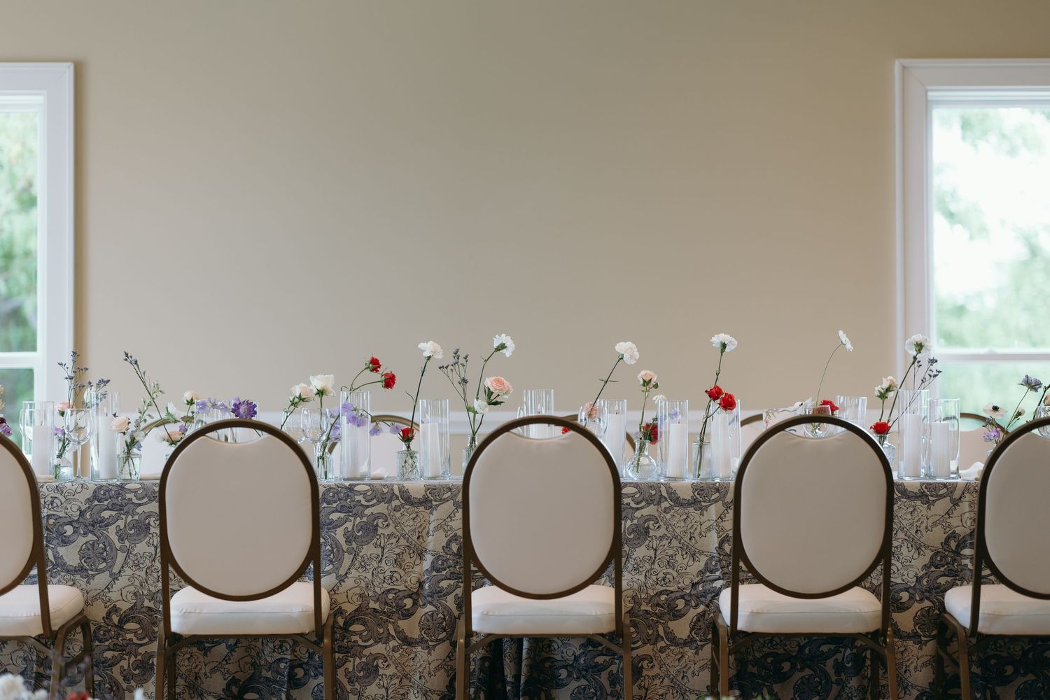 A row of chairs placed against a beige wall with small decorative ornaments on top create an elegant sitting area.