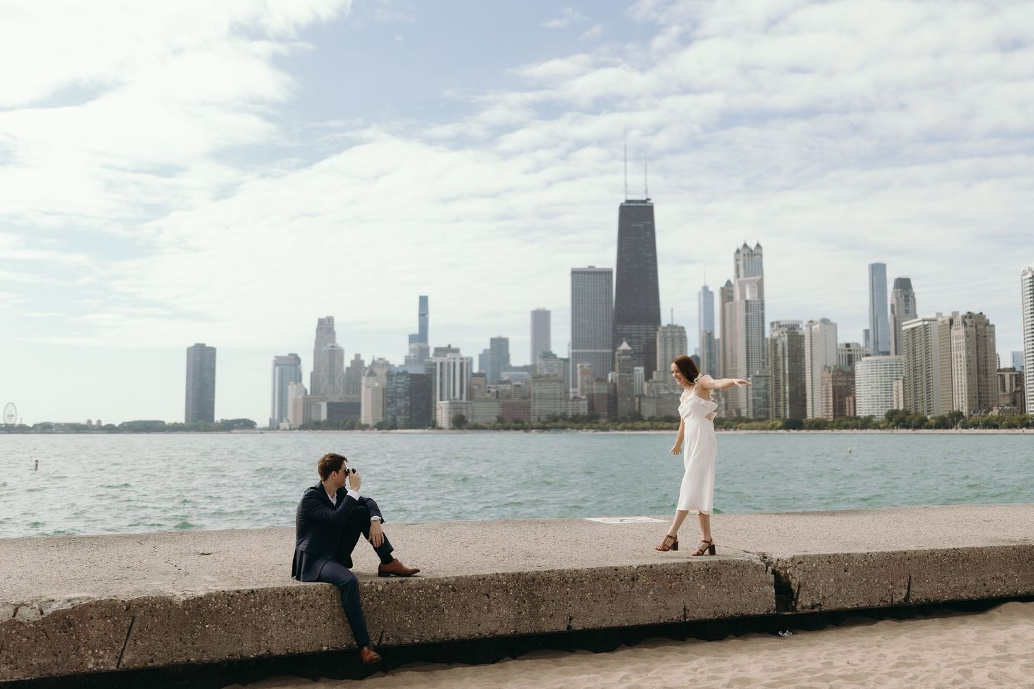 Couple posing separately along Chicago lakefront with dramatic skyline view.