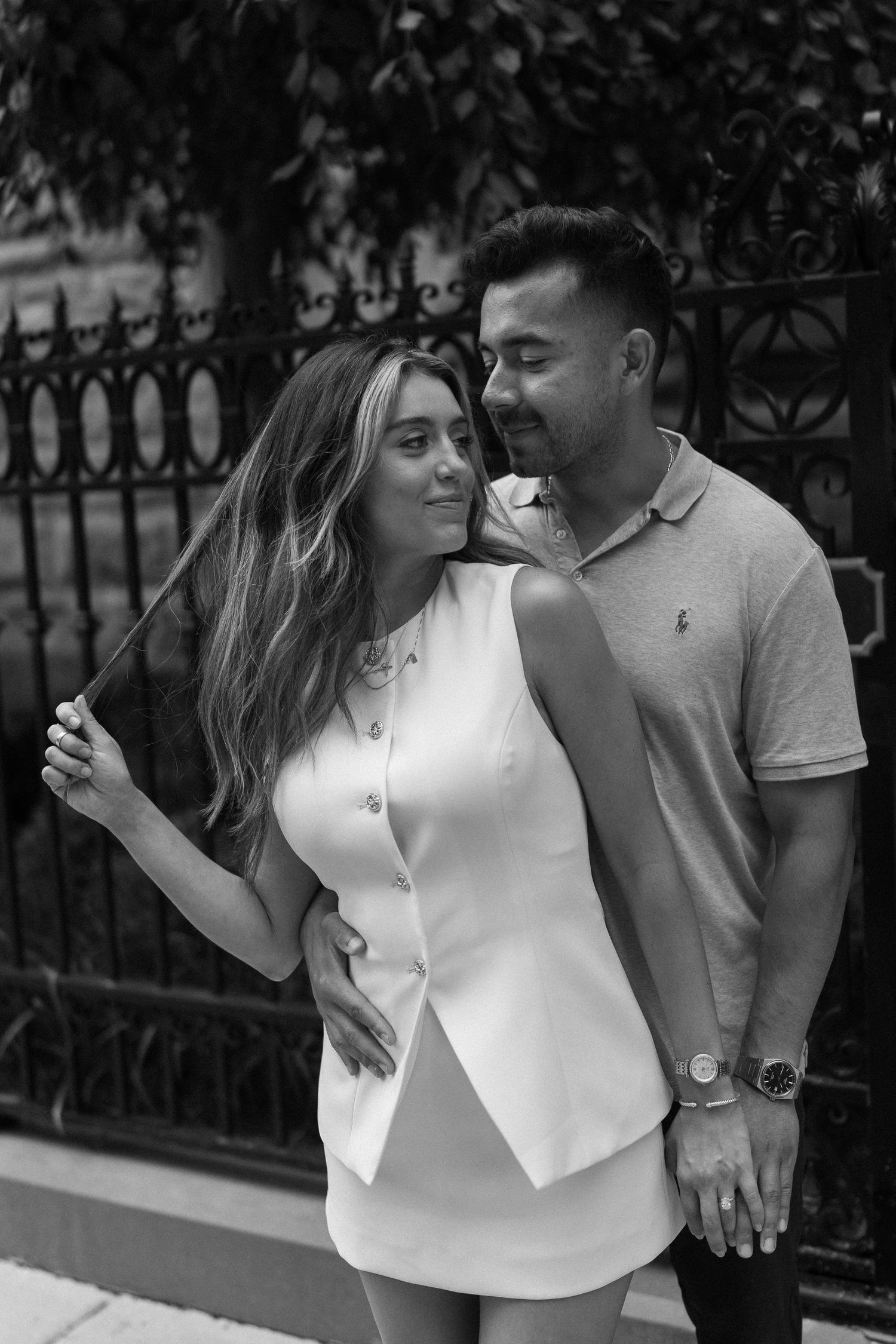 Black and white romantic couple photos showing tender moments between partners against an iron fence backdrop.