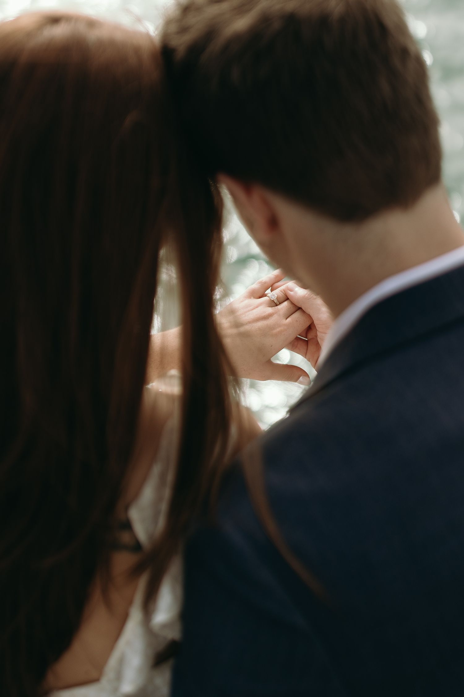 Intimate wedding moment captured showing clasped hands and gentle embrace.