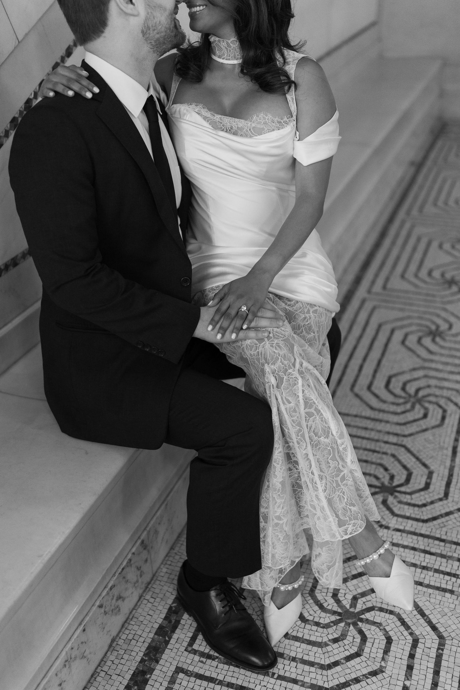 Intimate black and white portrait of couple on decorative tiled floor.