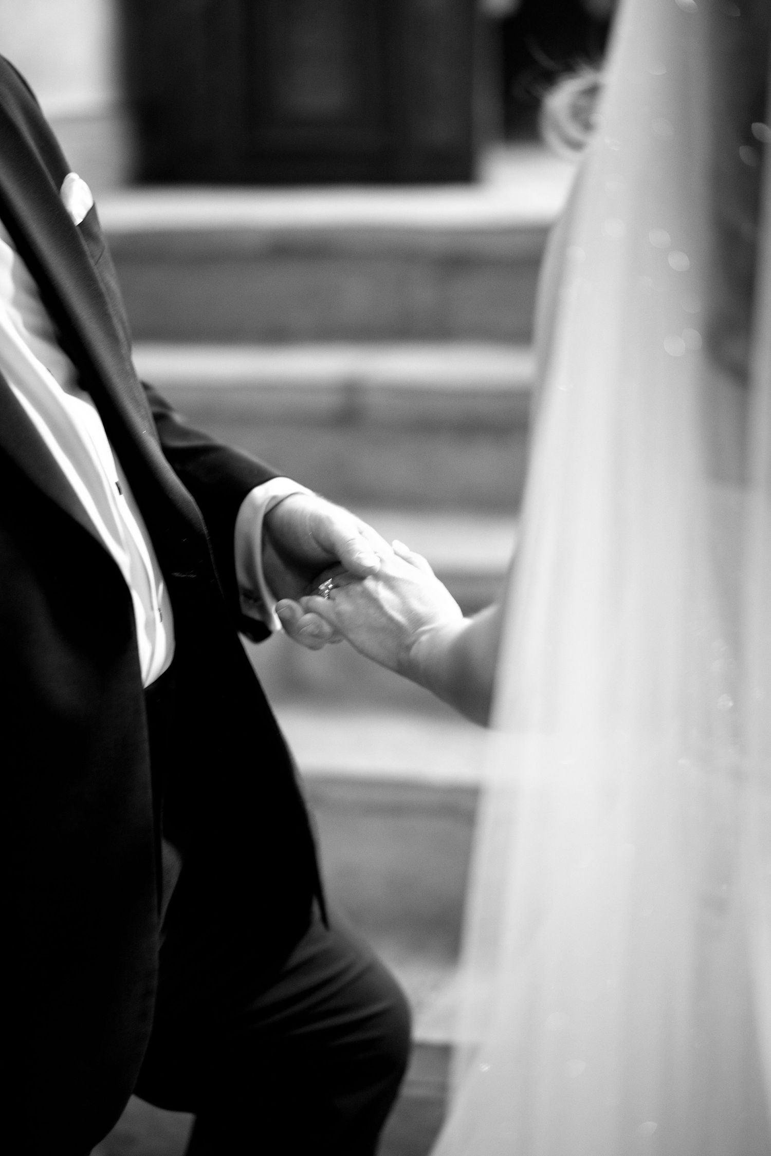 A black and white capture of a couple holding hands during their wedding ceremony.
