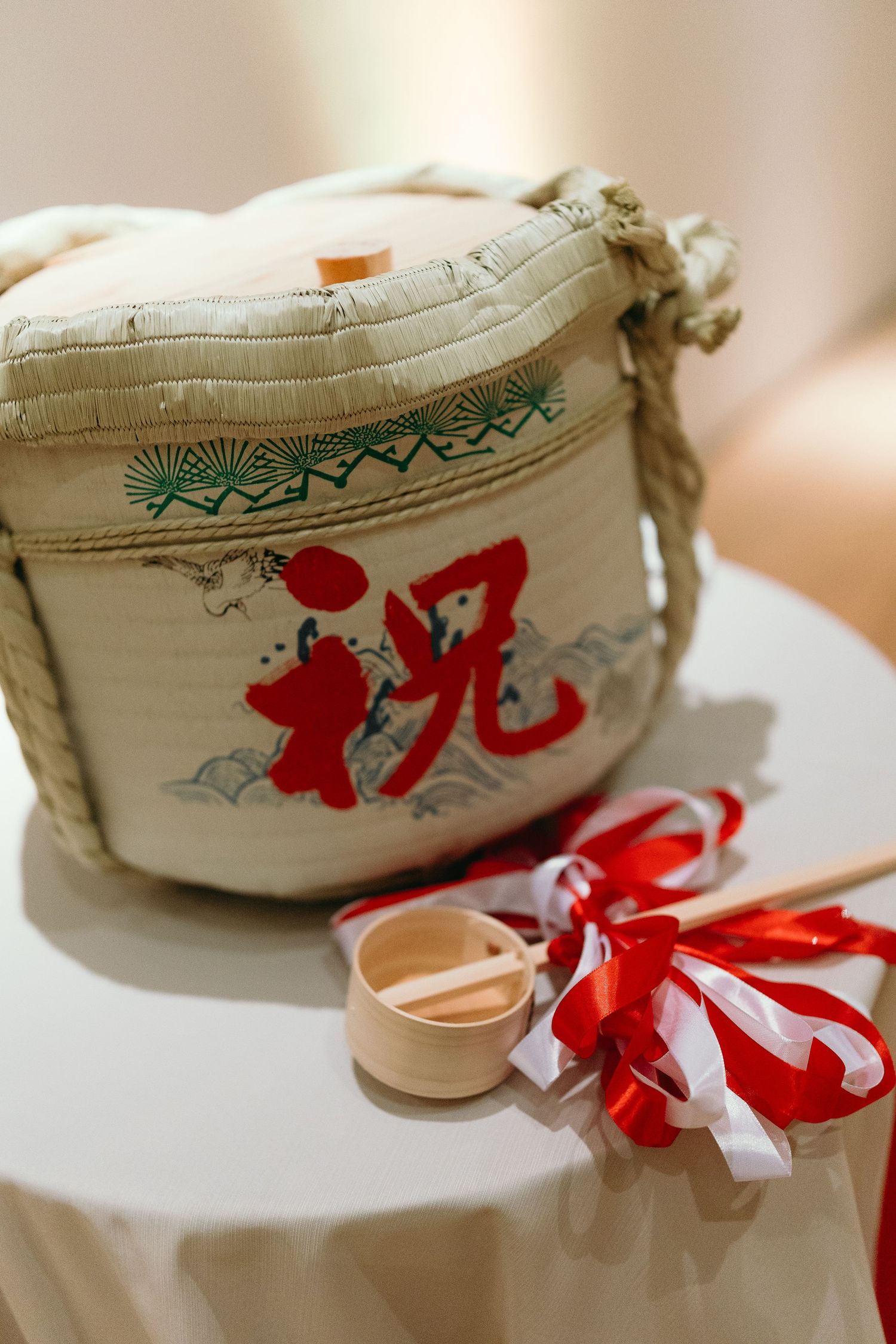 White ceramic jar decorated with red characters and ribbon details displayed on a table.
