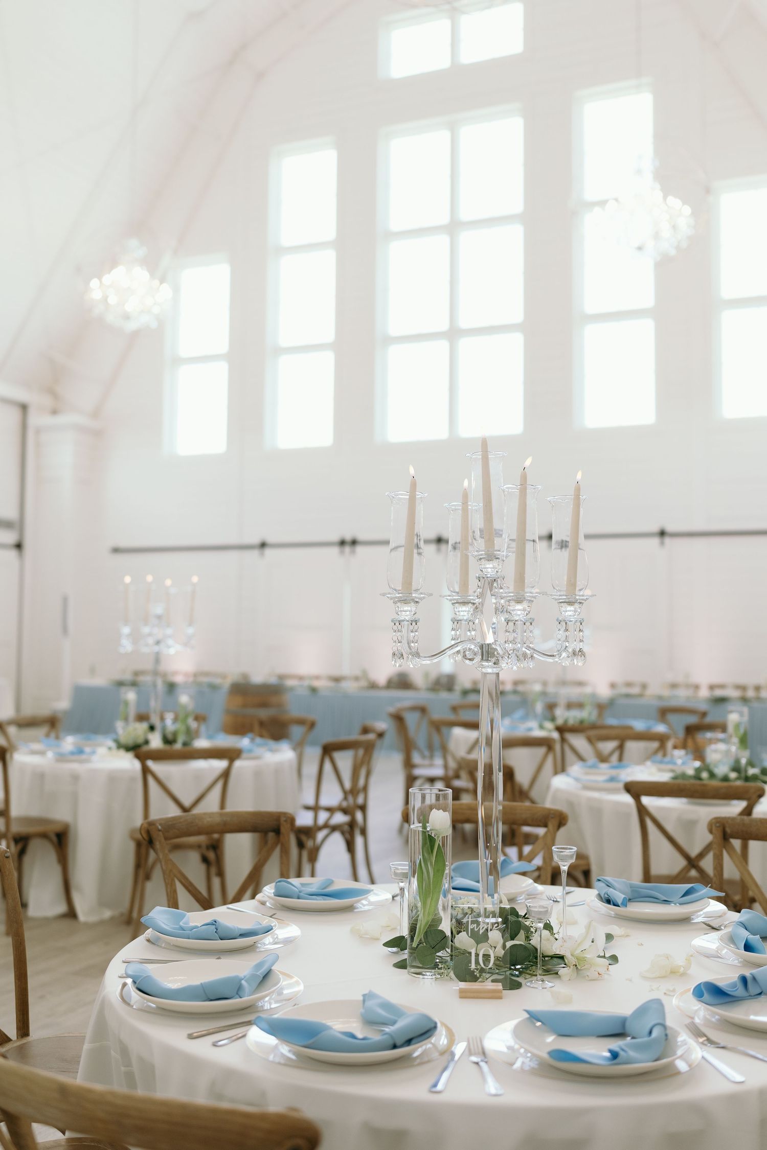 Elegant wedding reception table with blue accents, white linens, and crystal candelabra centerpiece.