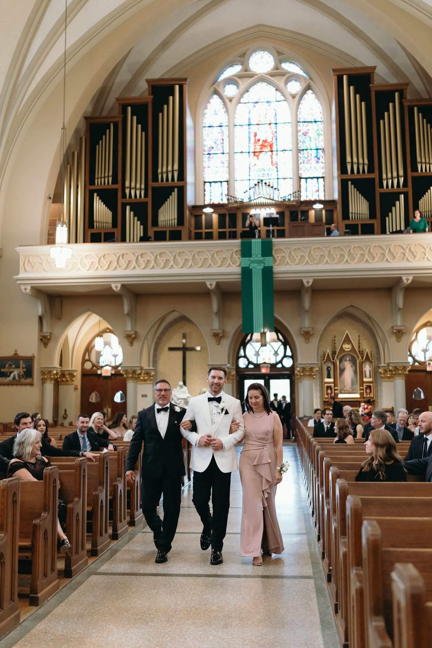 Traditional church interior with organ pipes and stained glass windows during wedding ceremony.