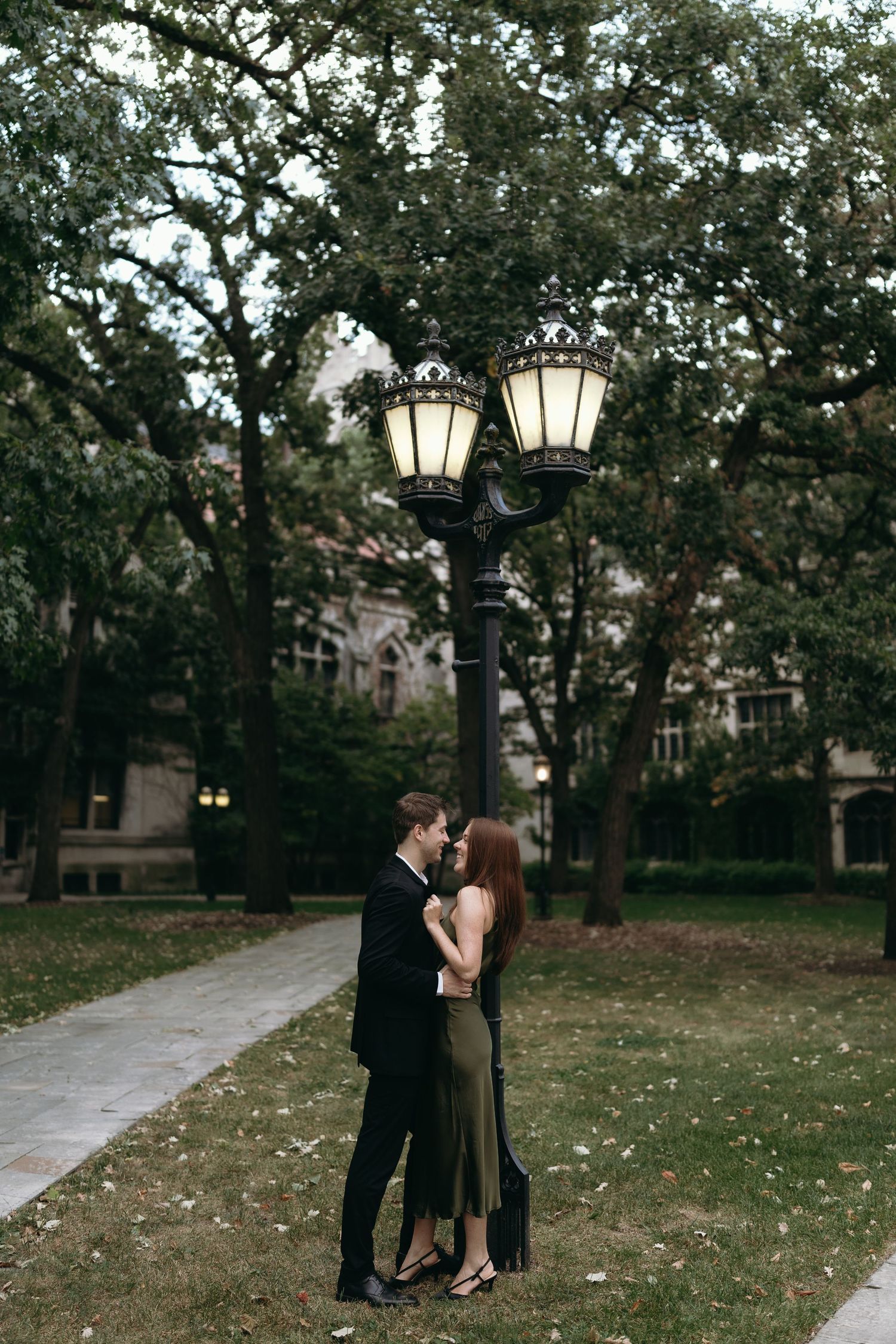 A couple embracing near a vintage lamp post on a romantic garden pathway.