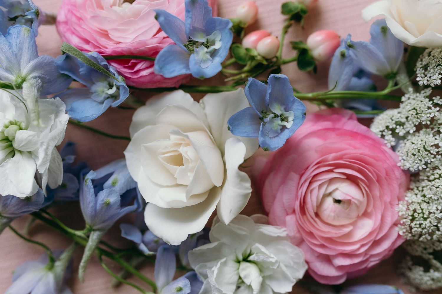 Beautiful floral arrangement with pink ranunculus, white roses, and blue hydrangeas.