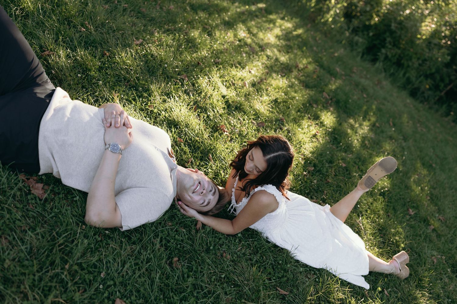 Series of romantic wedding photographs showing couple lying in lush green grass on a sunny day.