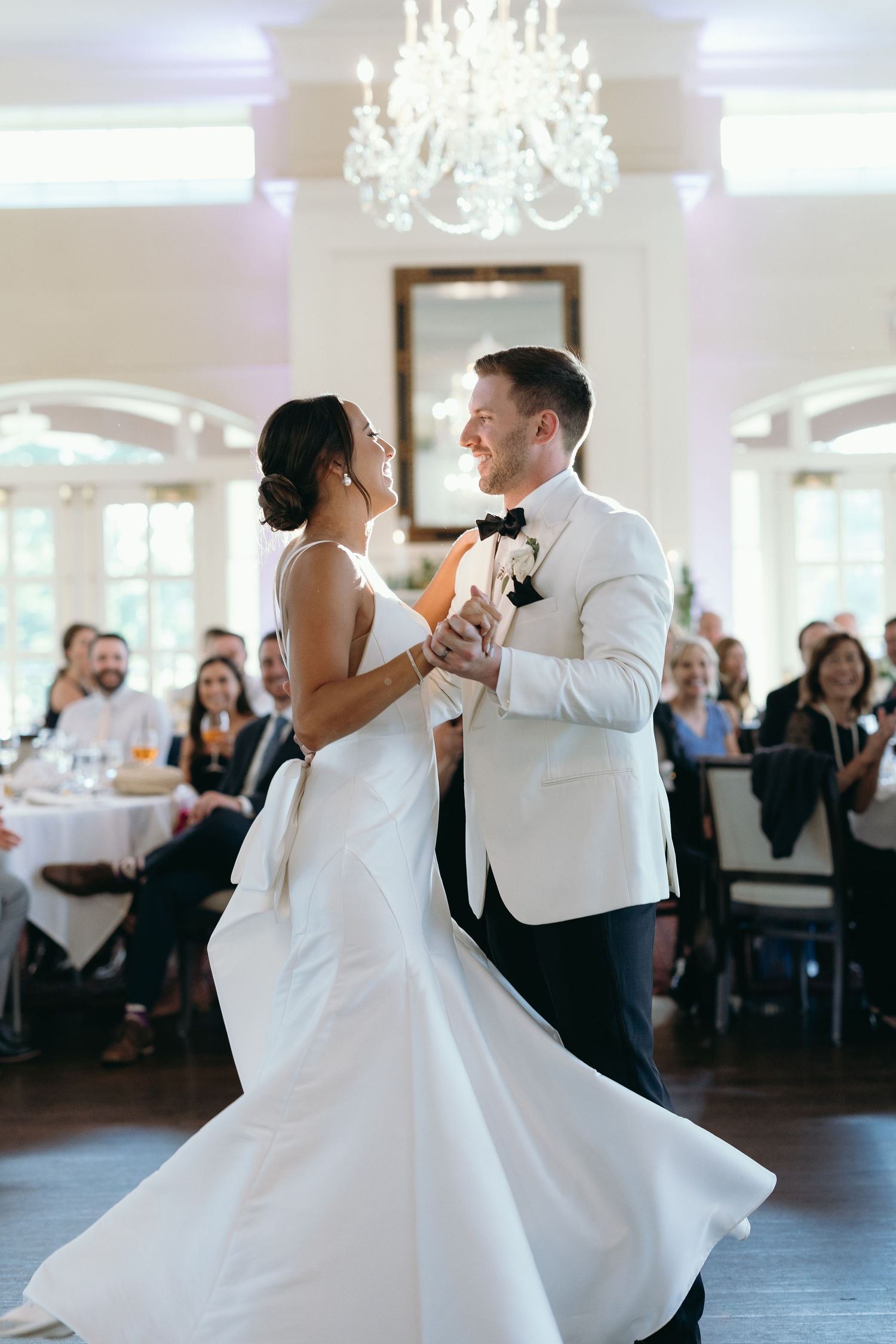 Couple performing their first dance under chandelier at wedding reception.