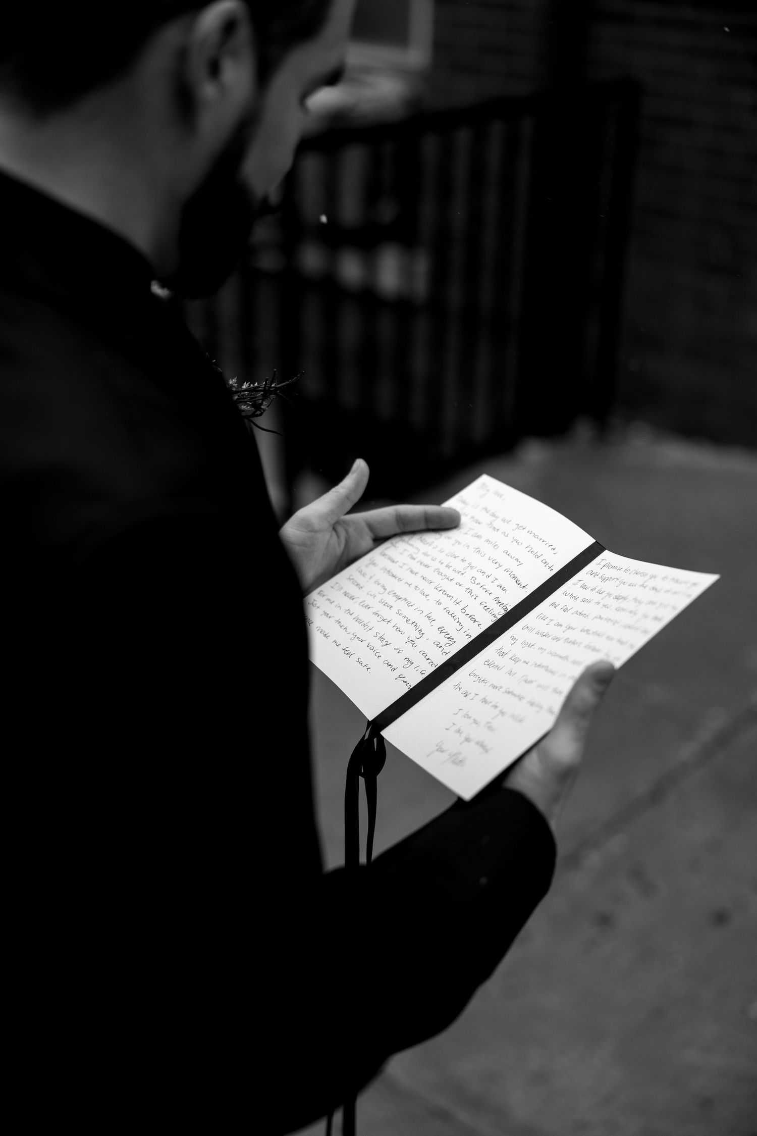 Hands hold handwritten notes in black and white dramatic lighting.