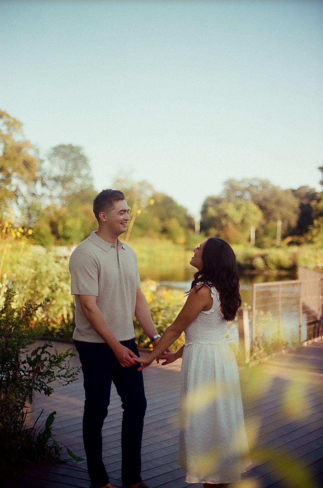 A romantic marriage proposal takes place on a rustic wooden deck at sunset.