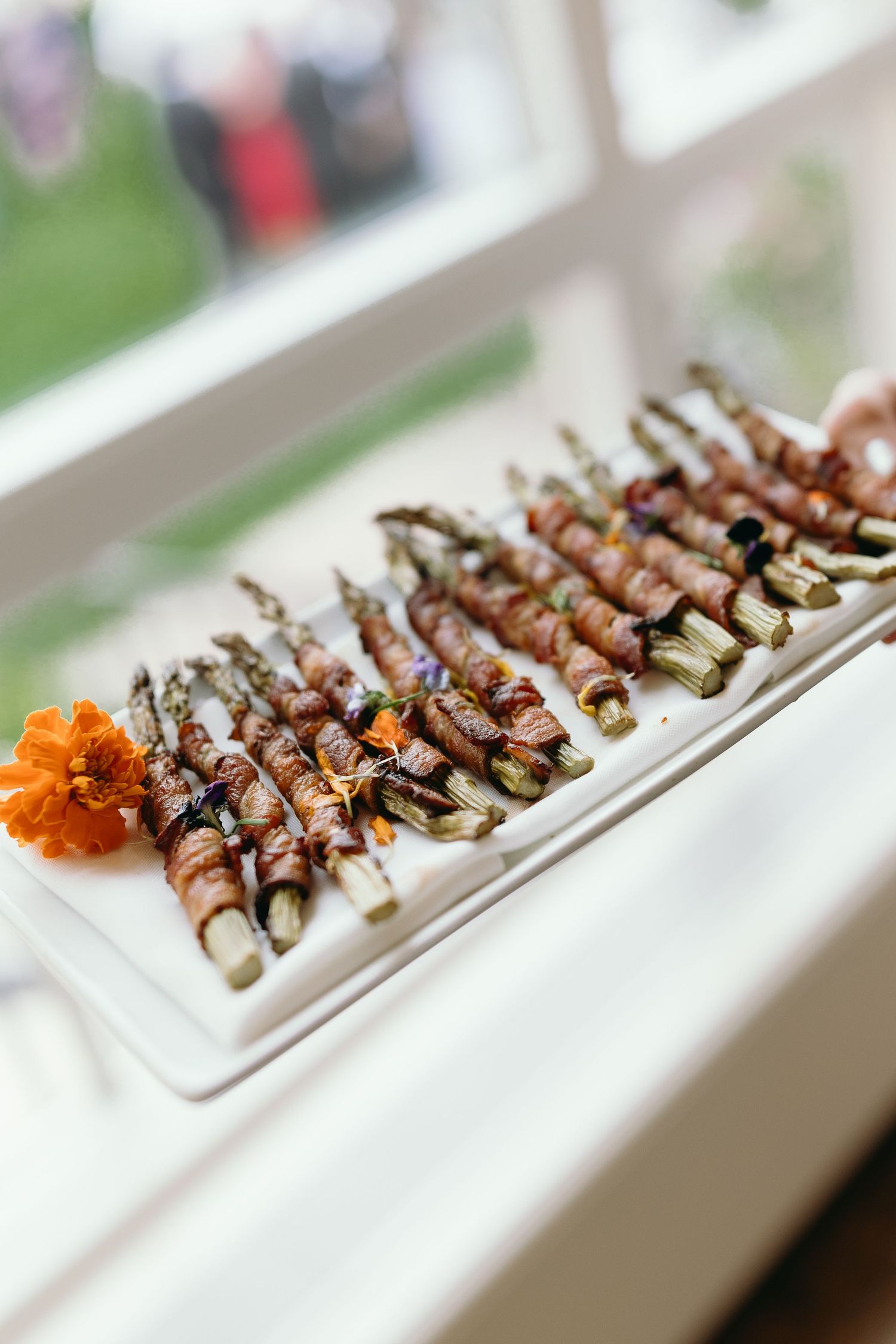 Elegant platter of bacon-wrapped appetizers garnished with an orange flower.