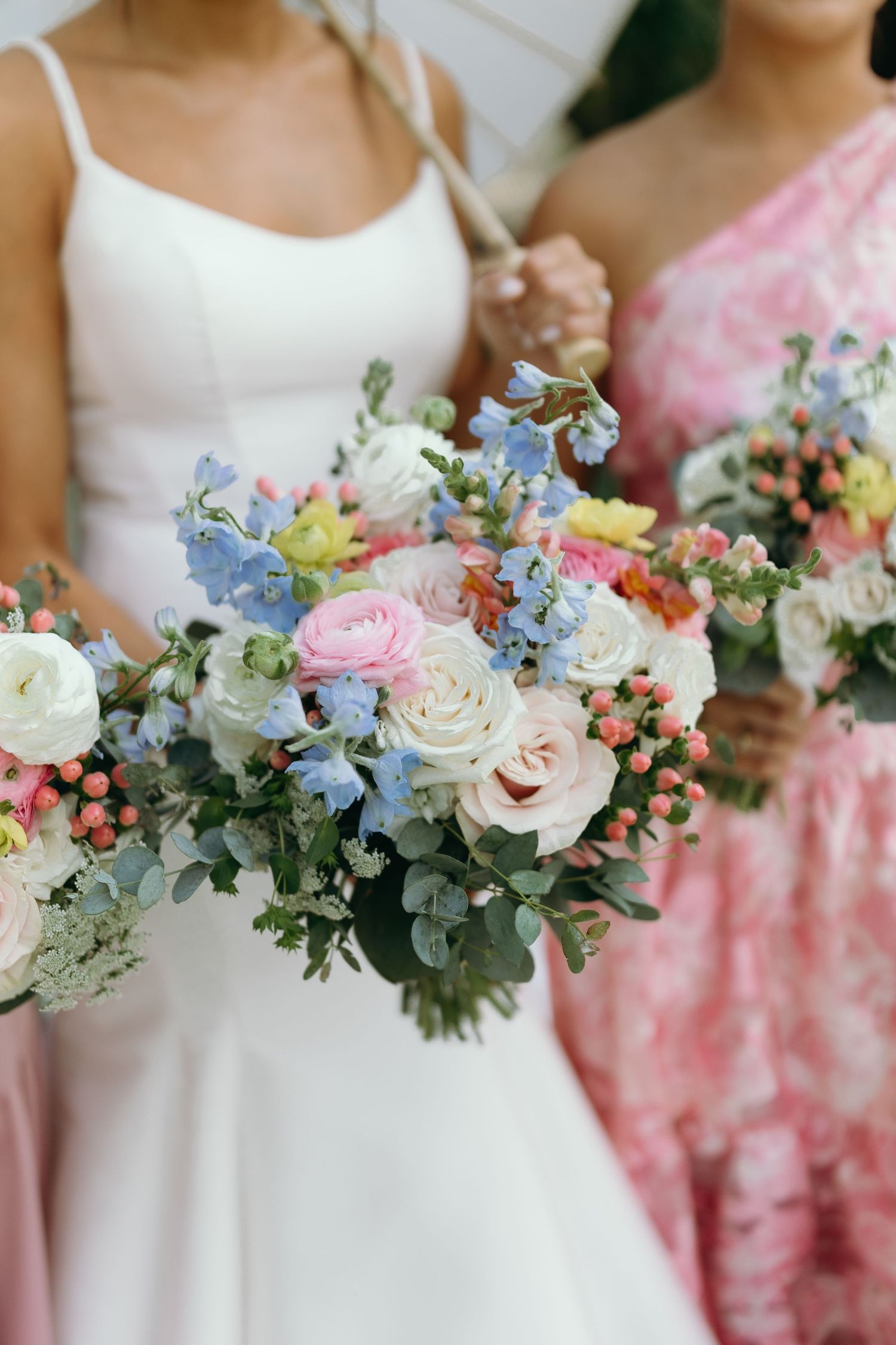 Beautiful pastel wedding bouquets featuring roses, delphiniums and eucalyptus in soft pink and blue tones.