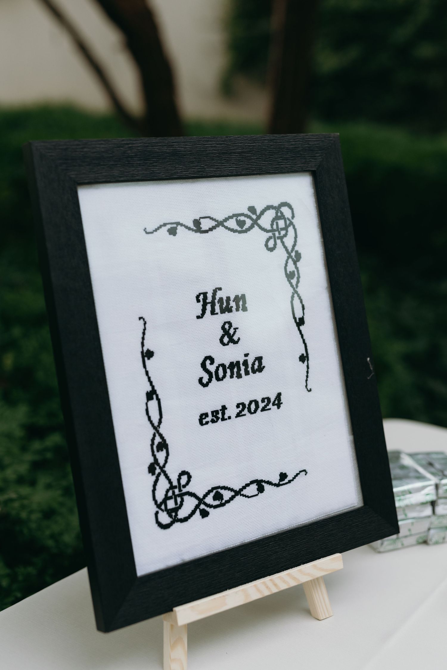 Wedding sign in black frame displaying 'Hun & Sonia est. 2024' with decorative borders.