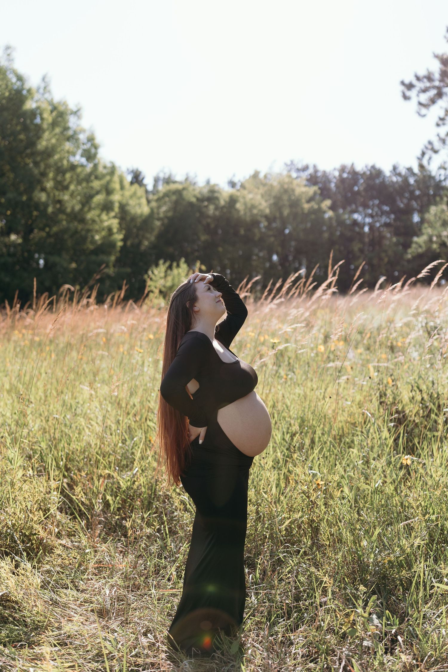 A woman in black stands in a sunlit meadow against a blue sky, photographed from multiple angles.