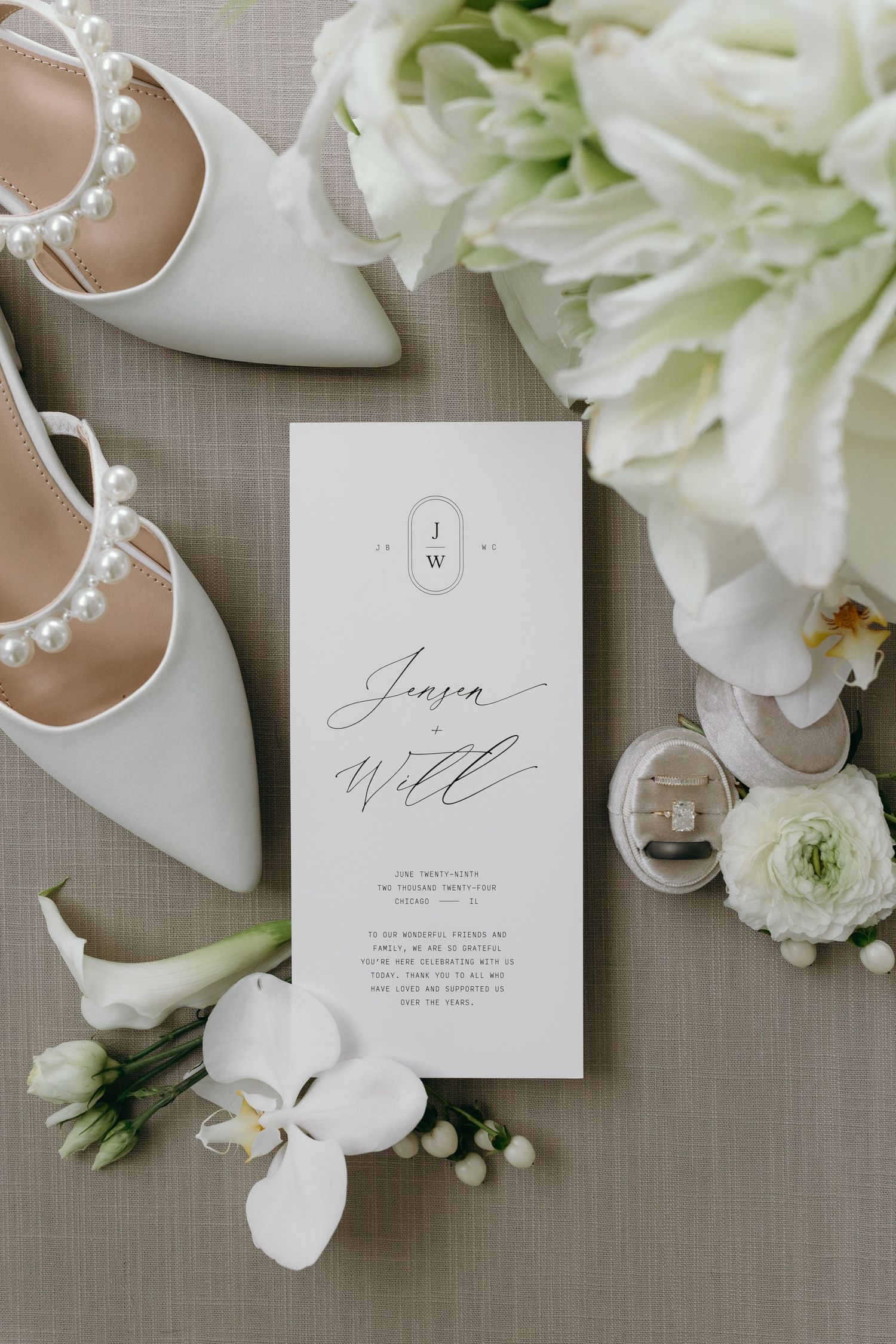 Wedding invitation surrounded by white bridal shoes, flowers and delicate floral details.