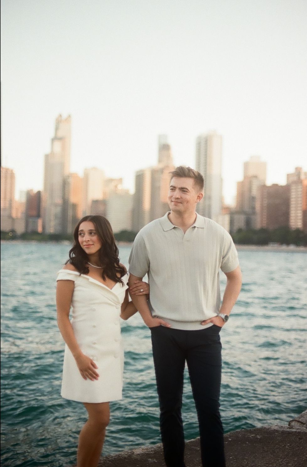 A couple poses together at sunset along the Chicago waterfront with the city skyline visible in the background.