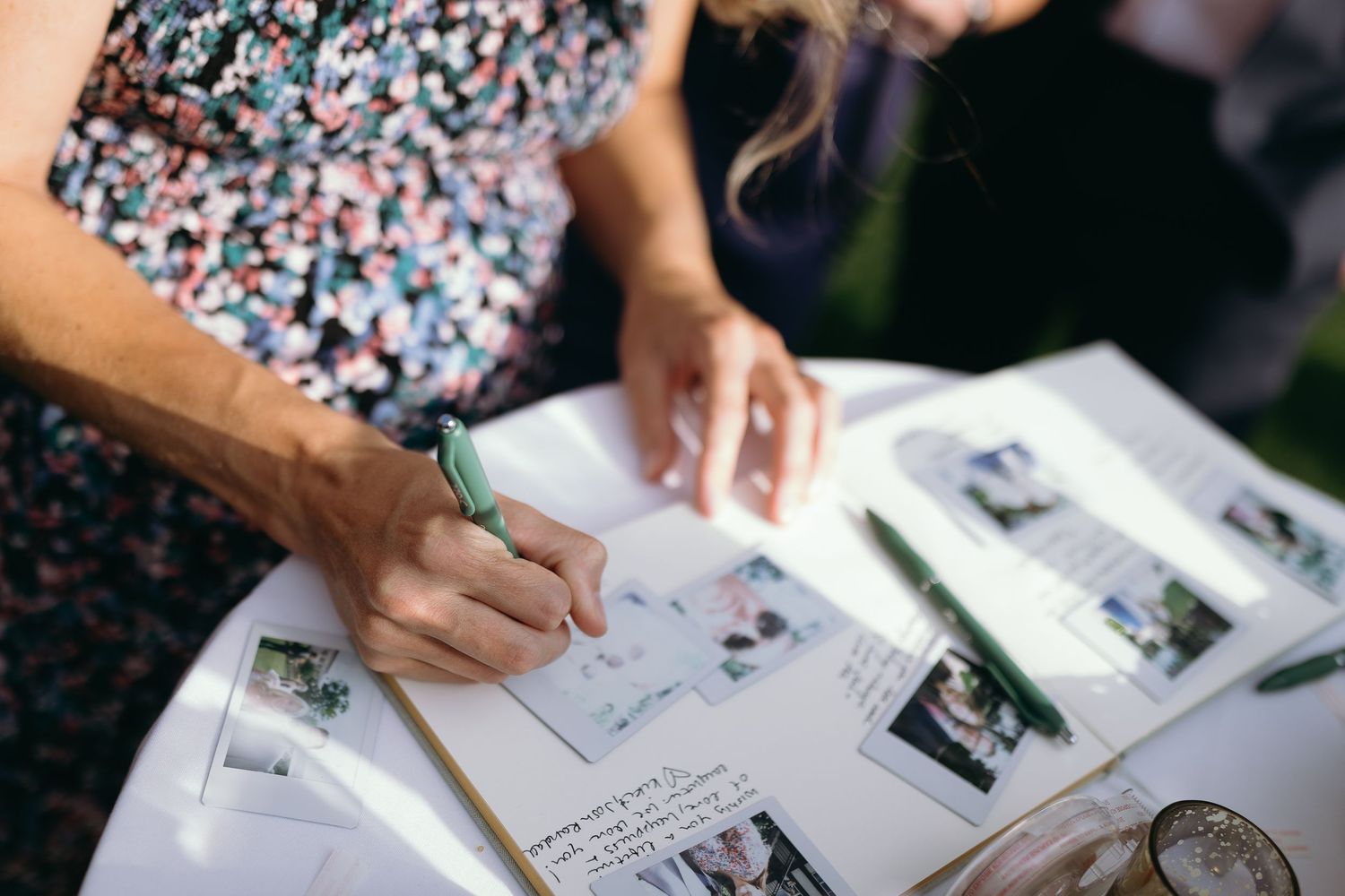 Guest signing a wedding guestbook filled with photos and memories.