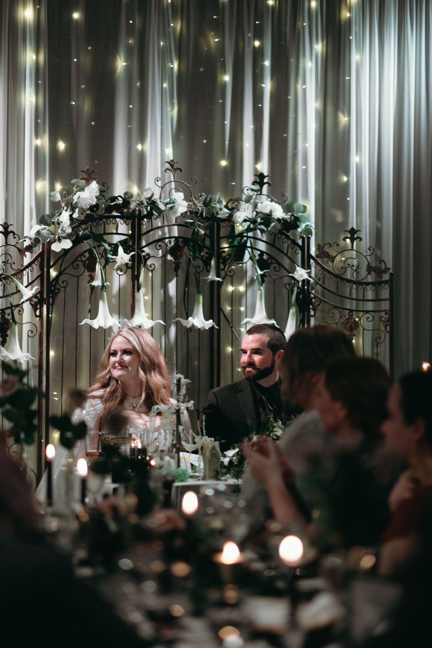 Wedding reception scene with fairy lights and floral arch decorations creating a romantic atmosphere.