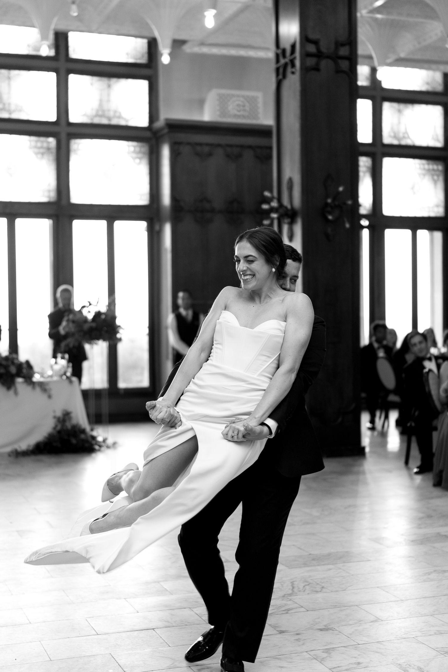 A playful dance move captured during a wedding reception in a bright indoor venue.