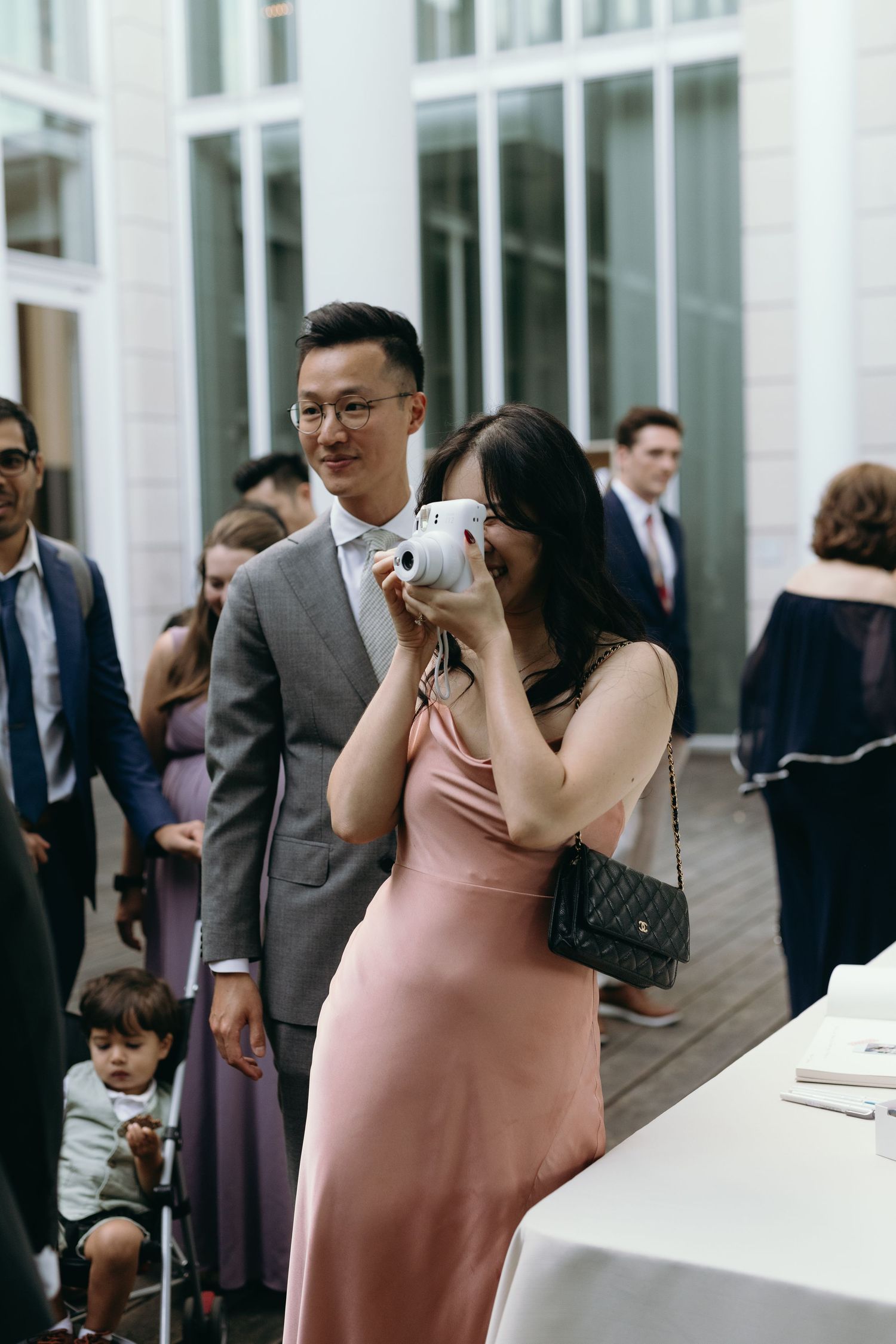 Wedding guests in formal attire taking photos at an outdoor reception.