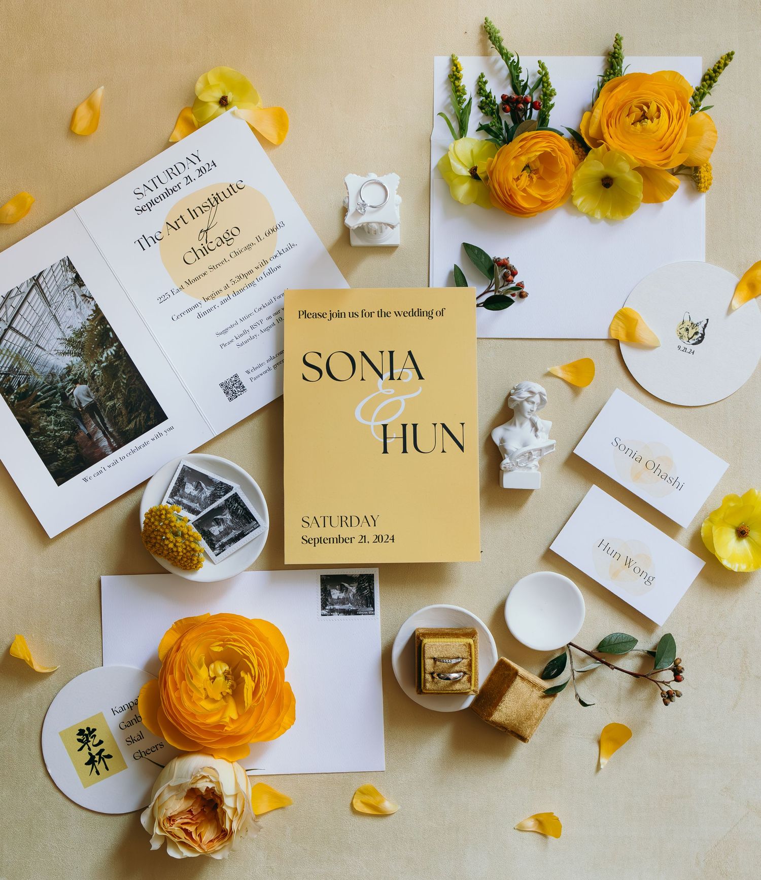 Wedding stationery flat lay with yellow roses, invitations and decorative elements on beige background.