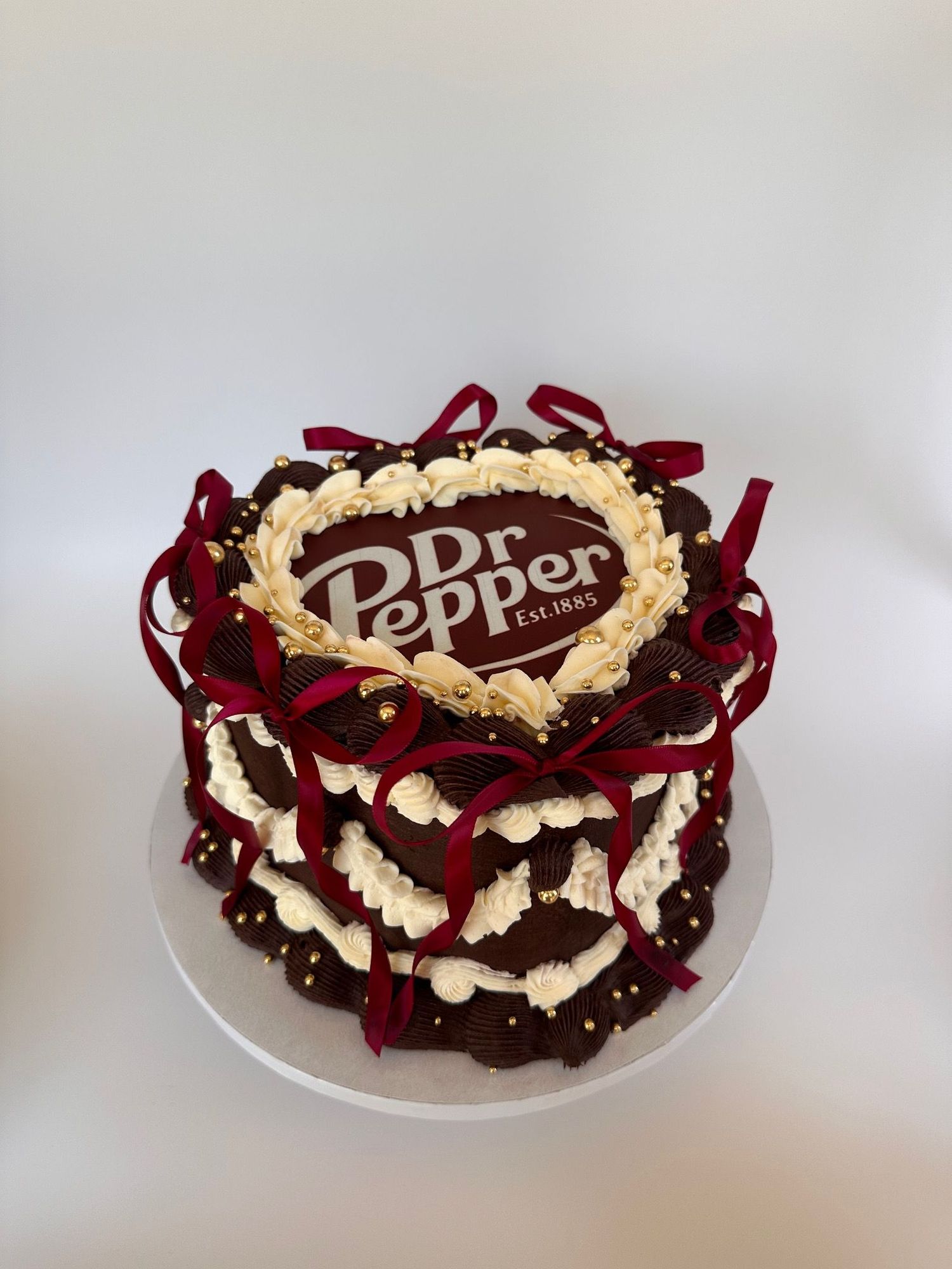 A chocolate cake decorated with swirling patterns of red velvet and cream cheese frosting on a white plate.