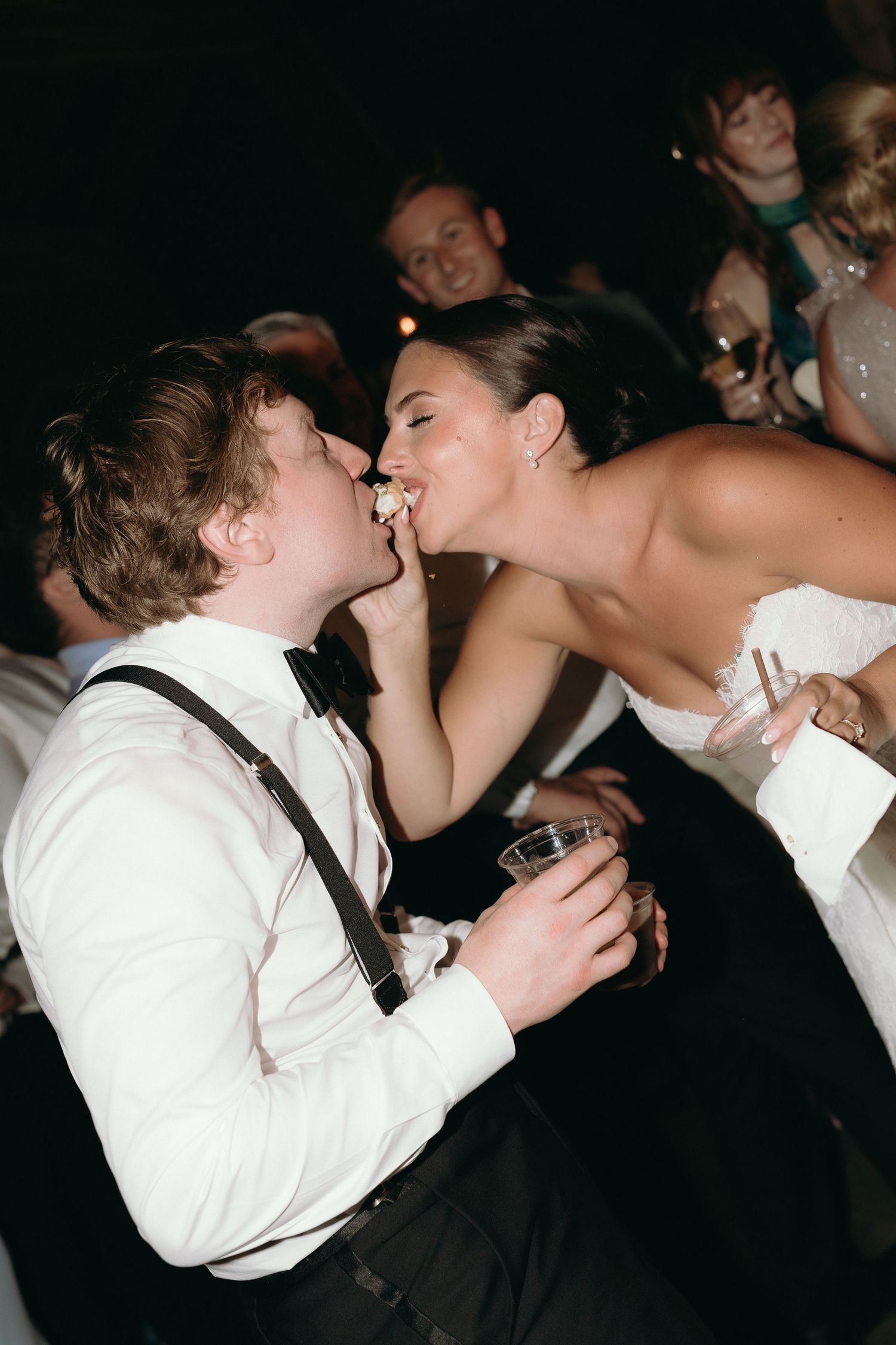 Bride and guest sharing a playful moment on the dance floor at a lively evening wedding reception.