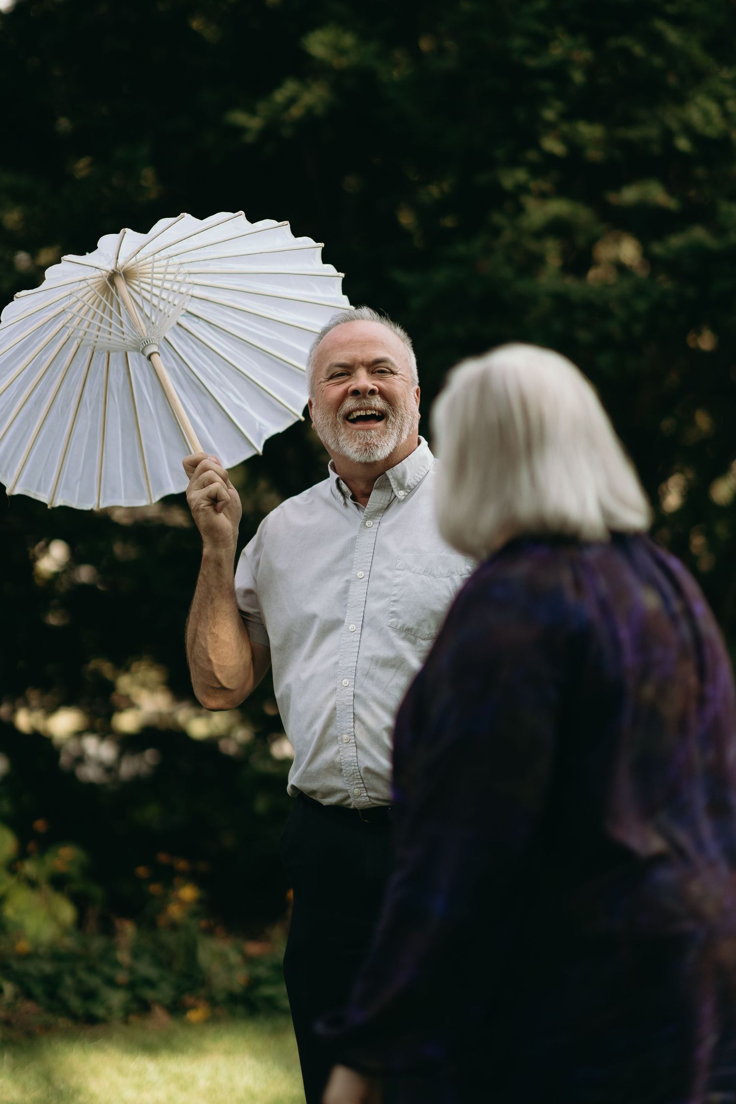 A moment of joy shared with a white paper parasol in a garden setting.