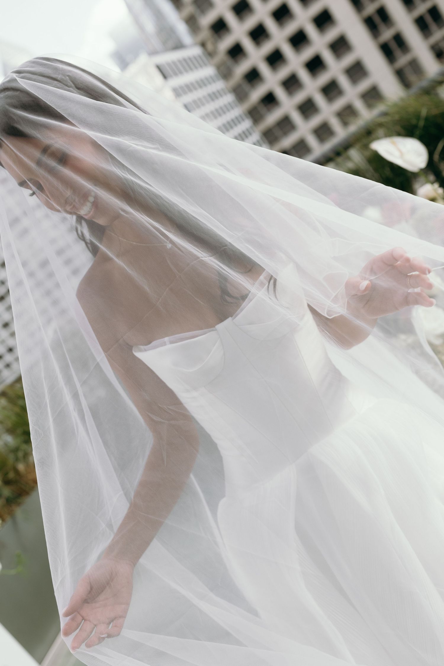 A flowing white wedding veil billows in the breeze revealing delicate bare feet underneath.
