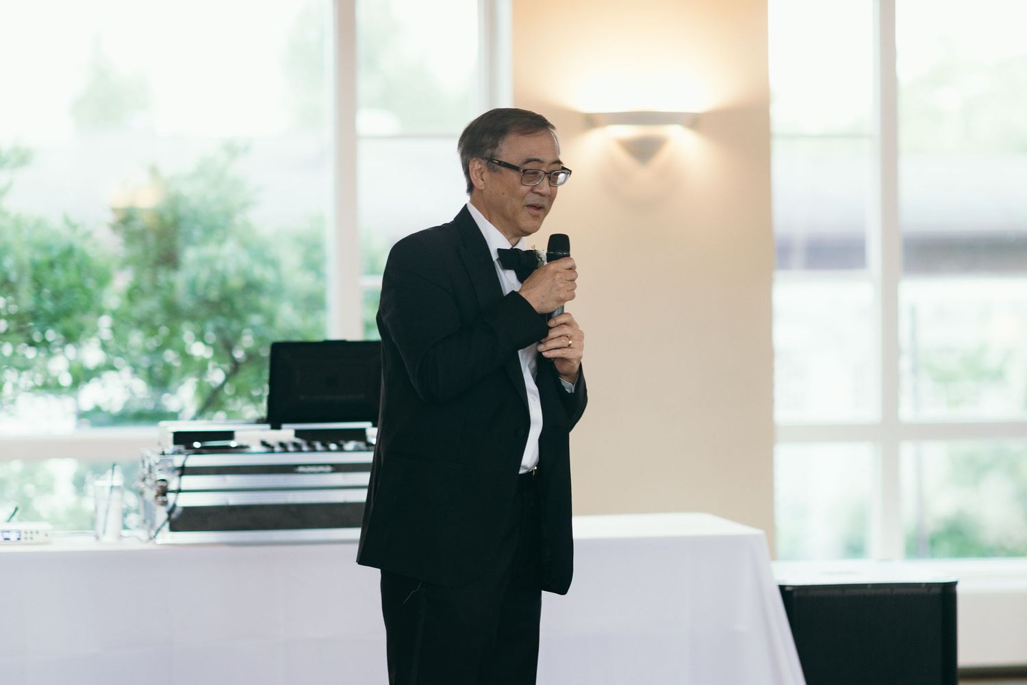 Speaker in formal attire giving a wedding toast at an elegant indoor venue.